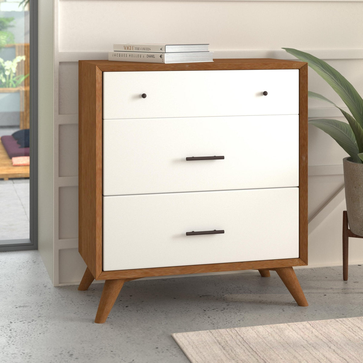 Three-drawer chest with a warm wood frame and white drawer fronts, shown beside a plant.