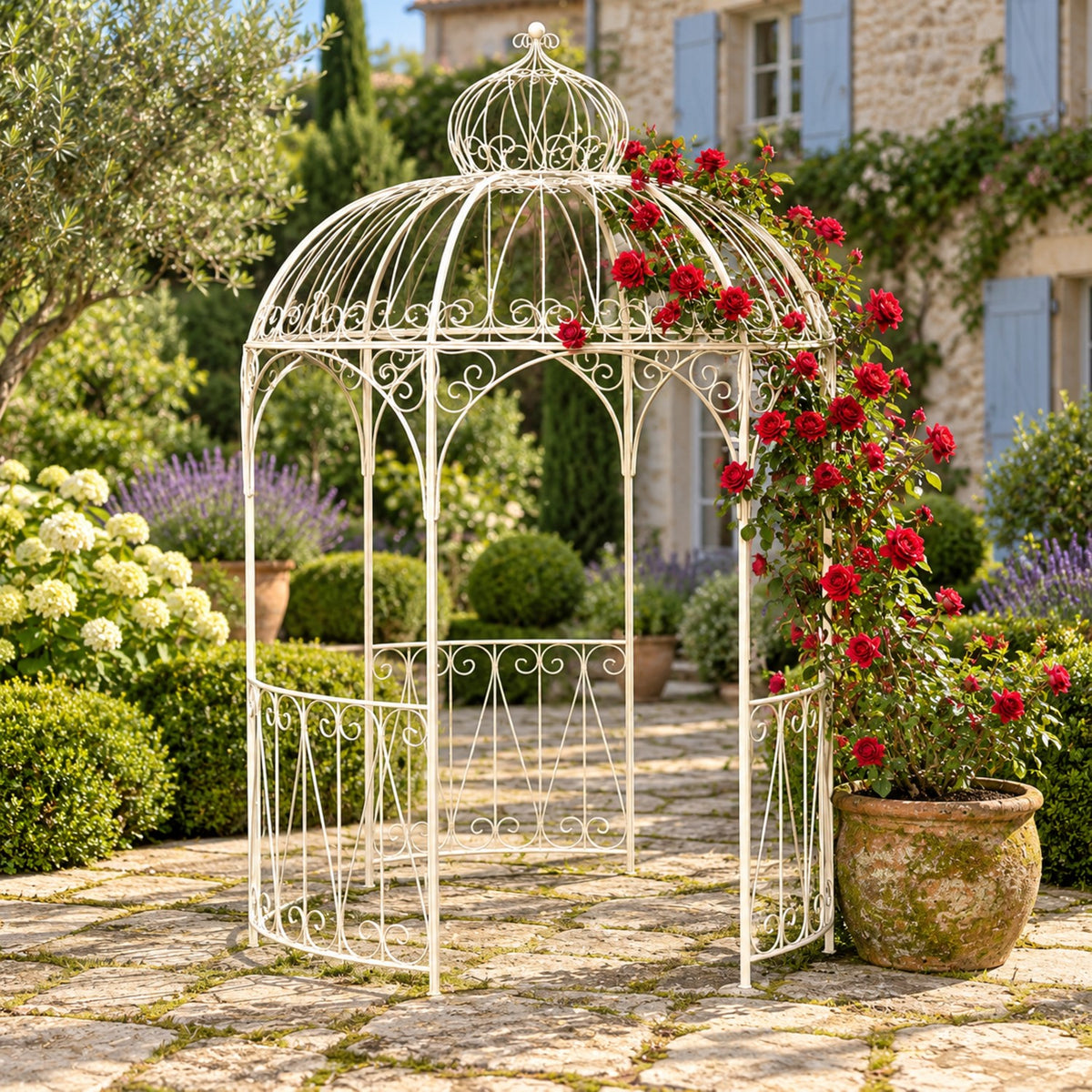 Antique white iron garden gazebo with flowers in a stone courtyard