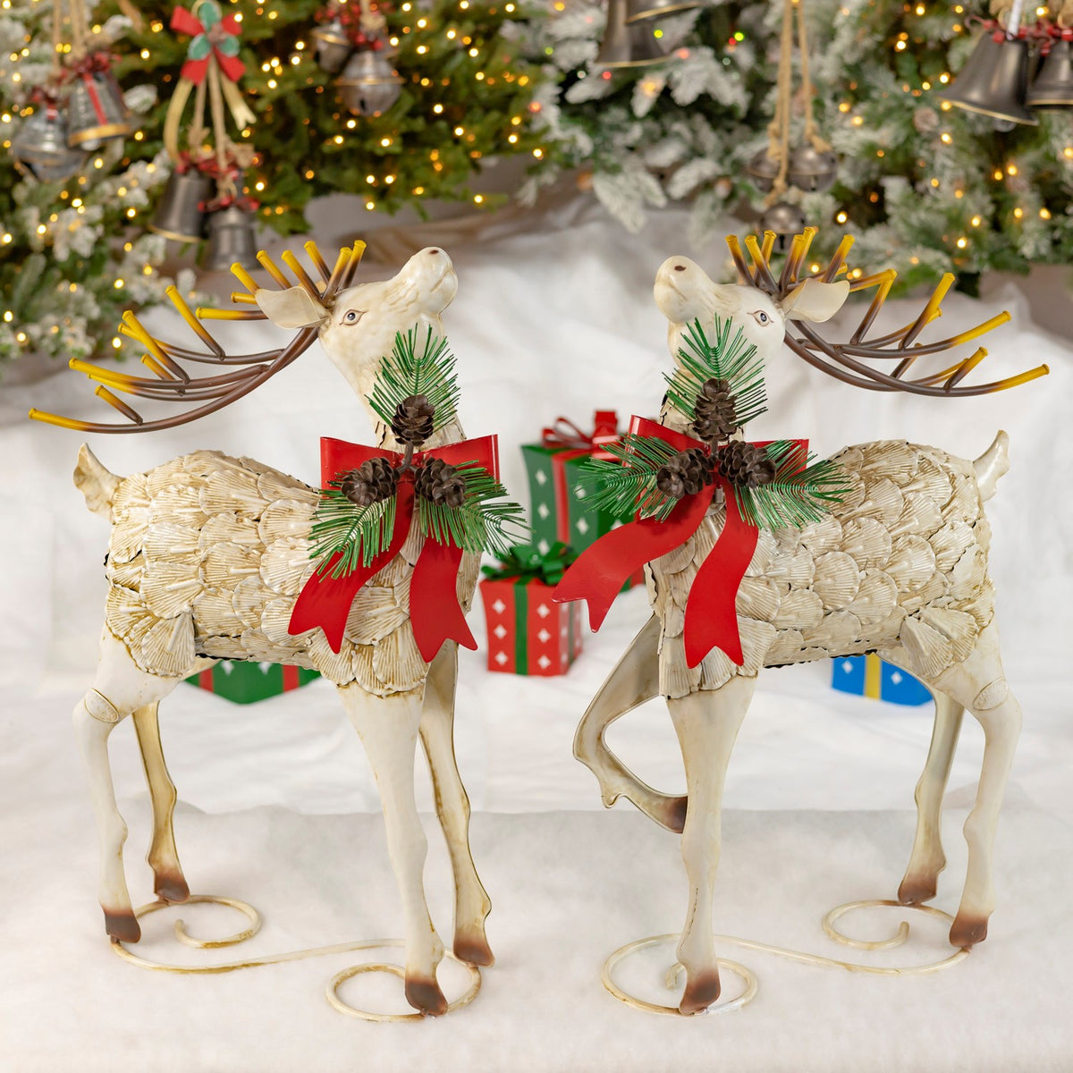 Pair of cream distressed iron reindeer with red bows in a festive holiday display