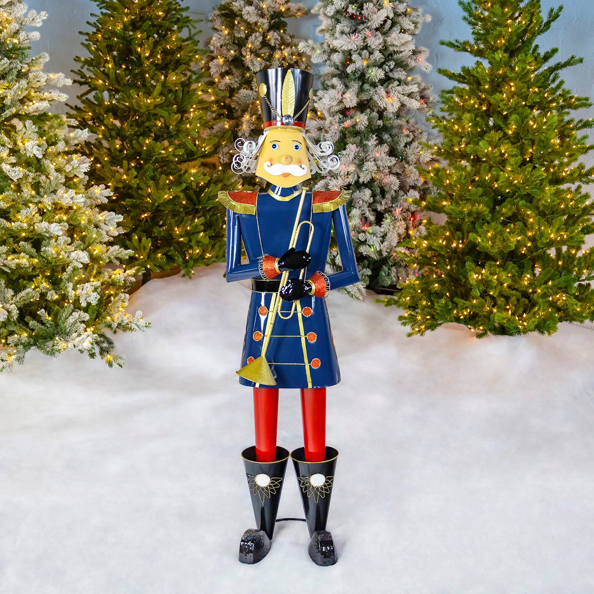 Full blue nutcracker soldier holding a trumpet, standing among decorated Christmas trees