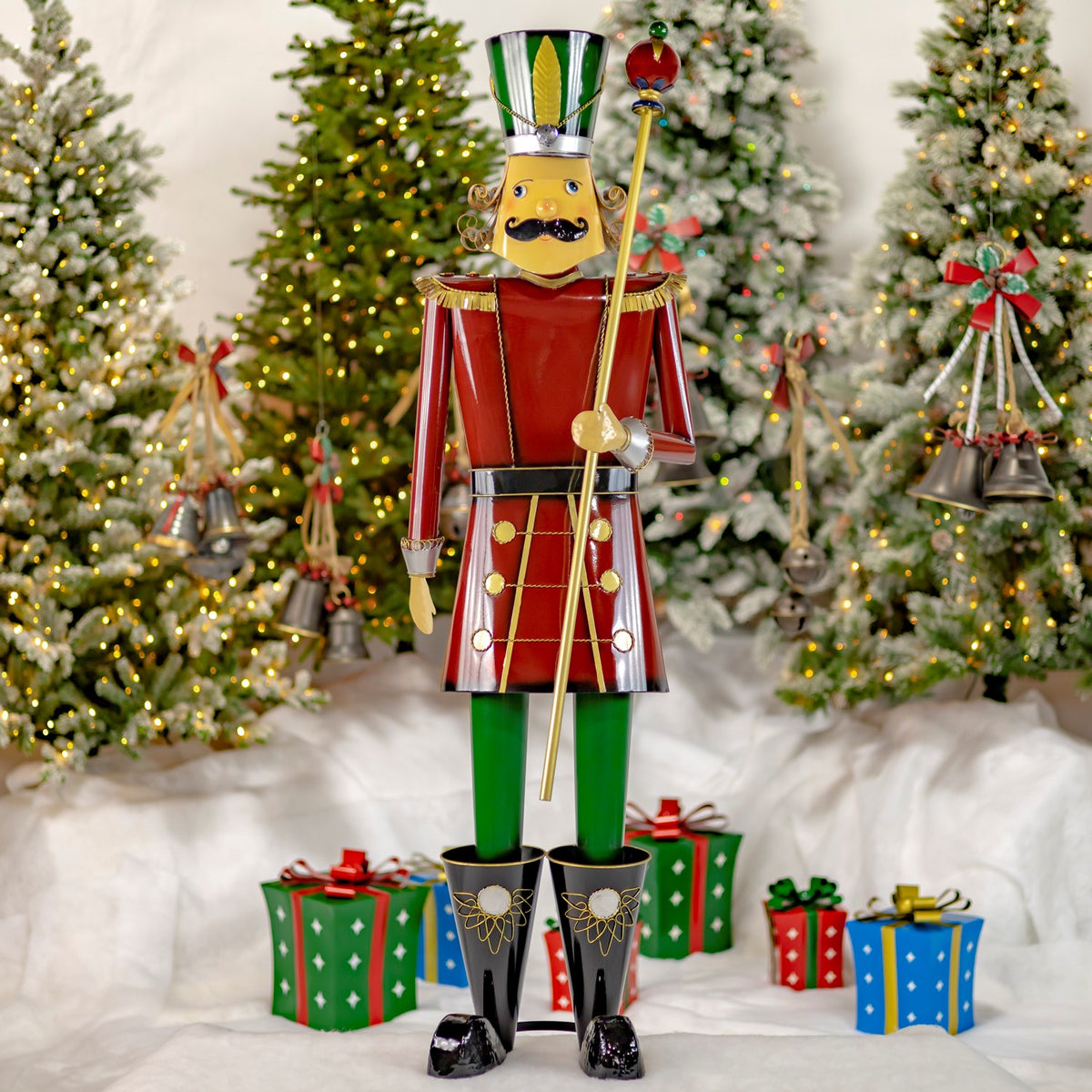 Full burgundy and gold nutcracker holding a baton among Christmas trees and gifts