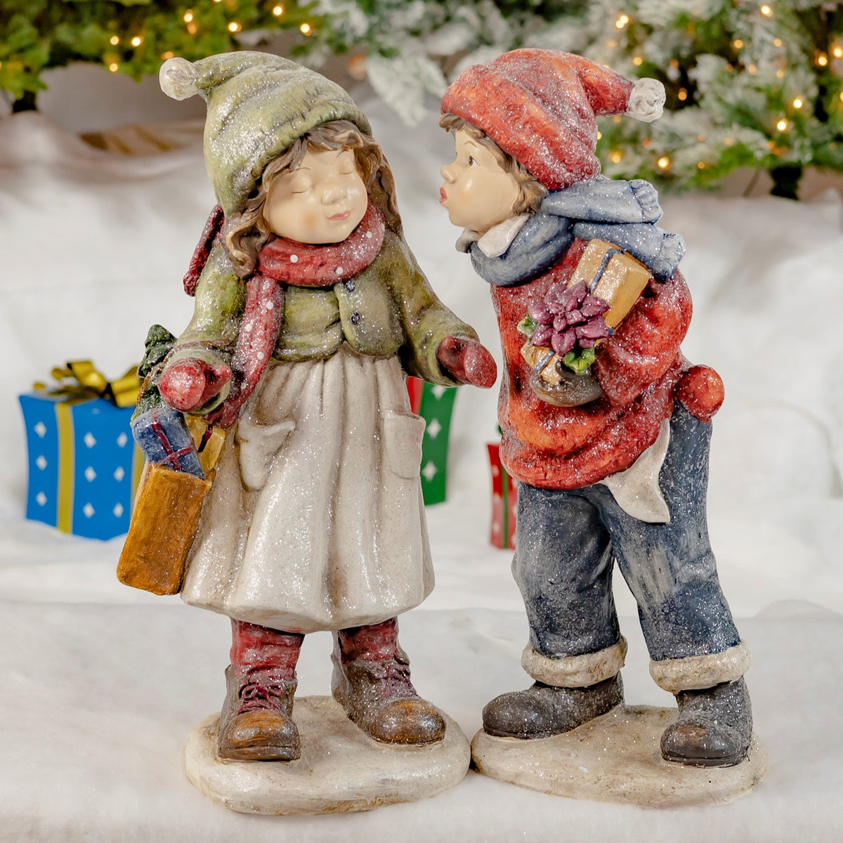 Girl and boy Christmas figurines with gifts, shown together from the front