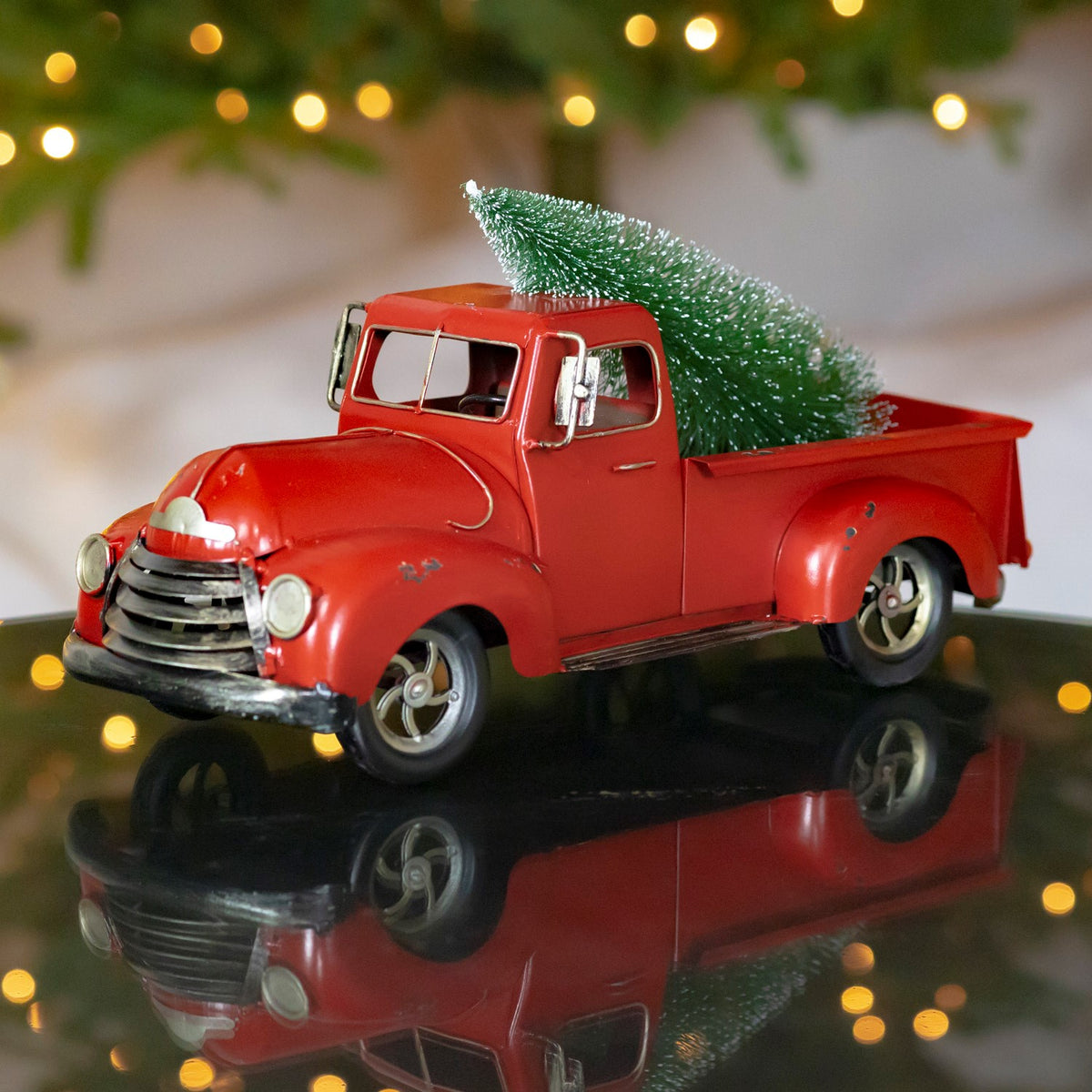 Distressed red vintage pickup carrying a small evergreen tree, shown from the front and passenger side.
