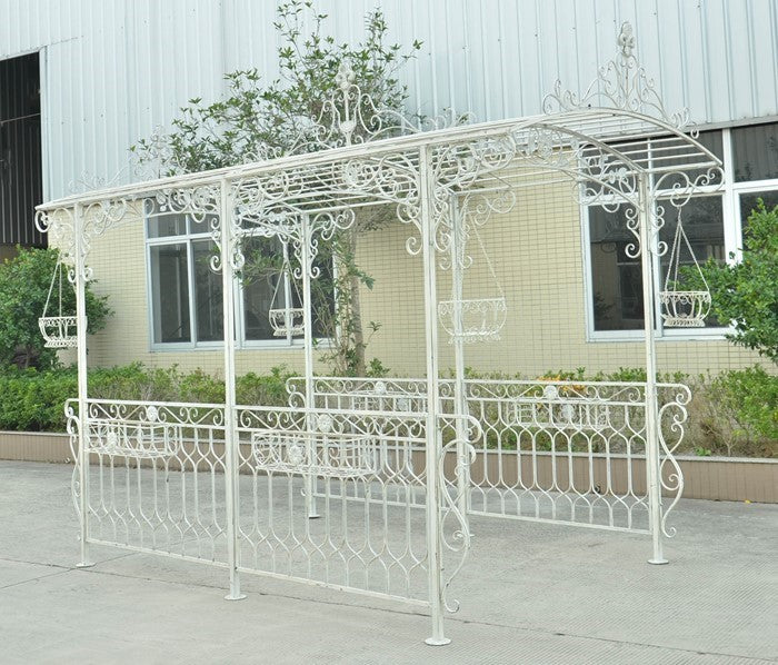 Antique white ornate iron gazebo with side fencing shown outdoors from an angled front view