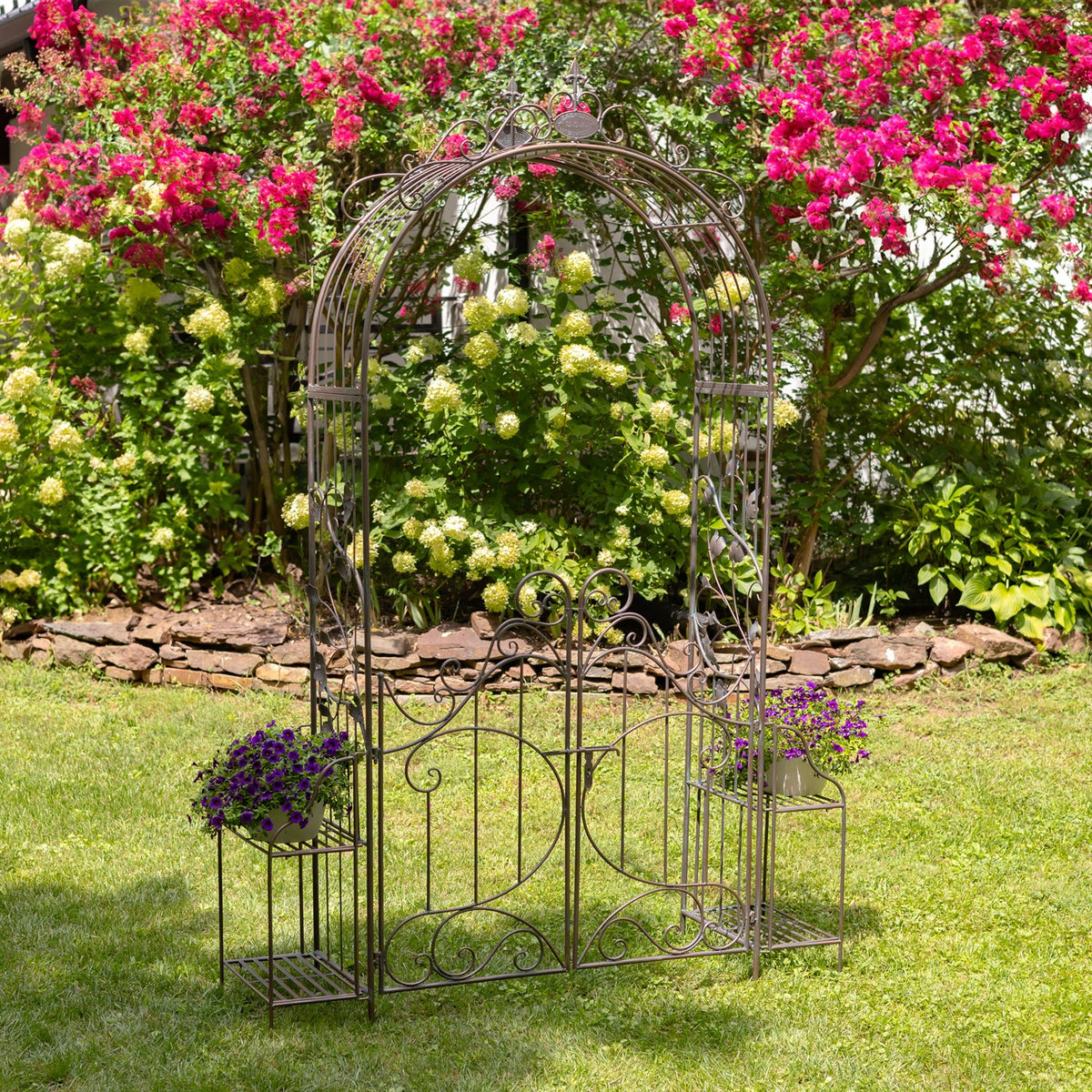 Copper-toned iron garden gate arch with side plant stands on a lawn