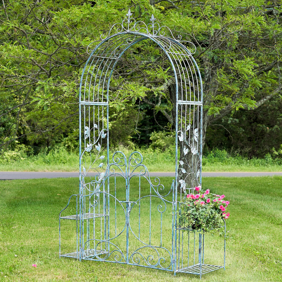 Light blue iron garden gate arch with side plant stands beside a garden path