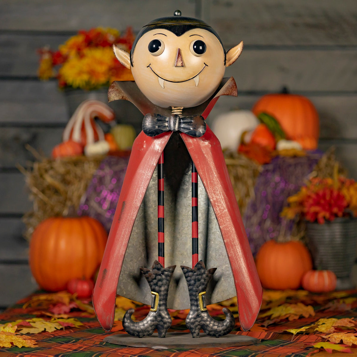 Full front view of a vampire figurine with red cape and black-and-red striped legs