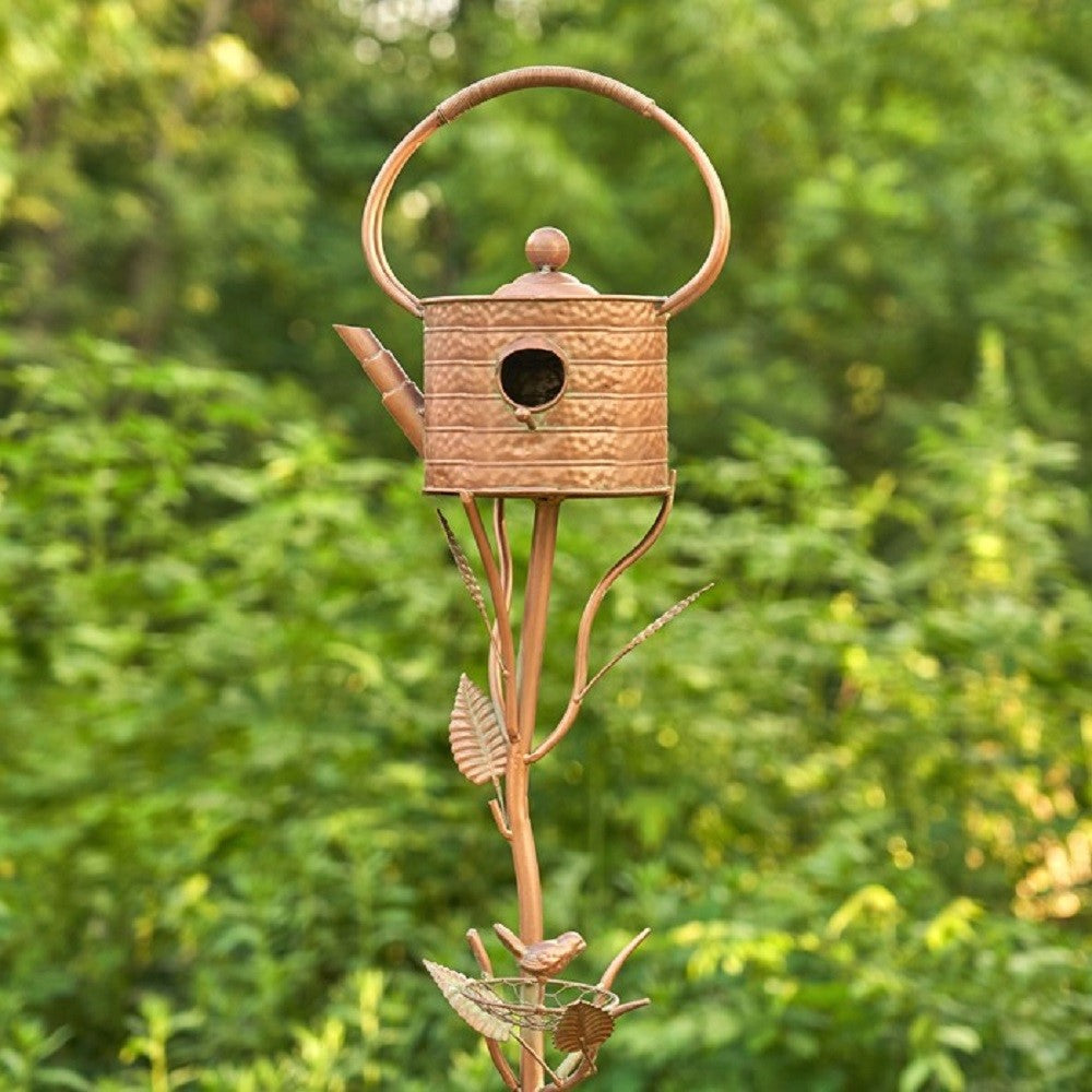 Antique copper teapot birdhouse stake shown full-length among green garden foliage