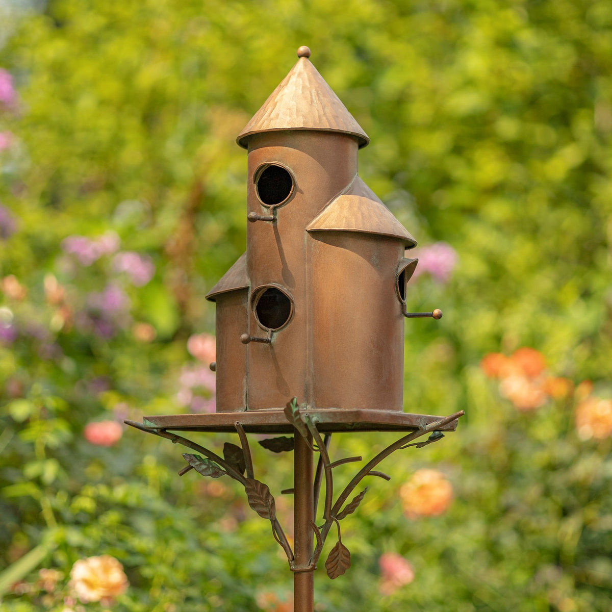 Antique copper triple birdhouse stake among colorful garden flowers