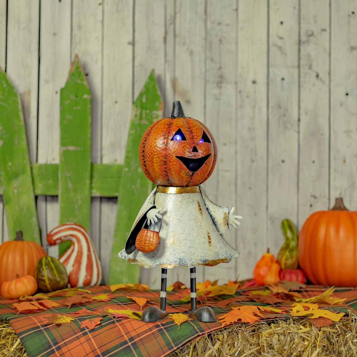 Orange jack-o'-lantern ghost figurine standing among pumpkins in an autumn display