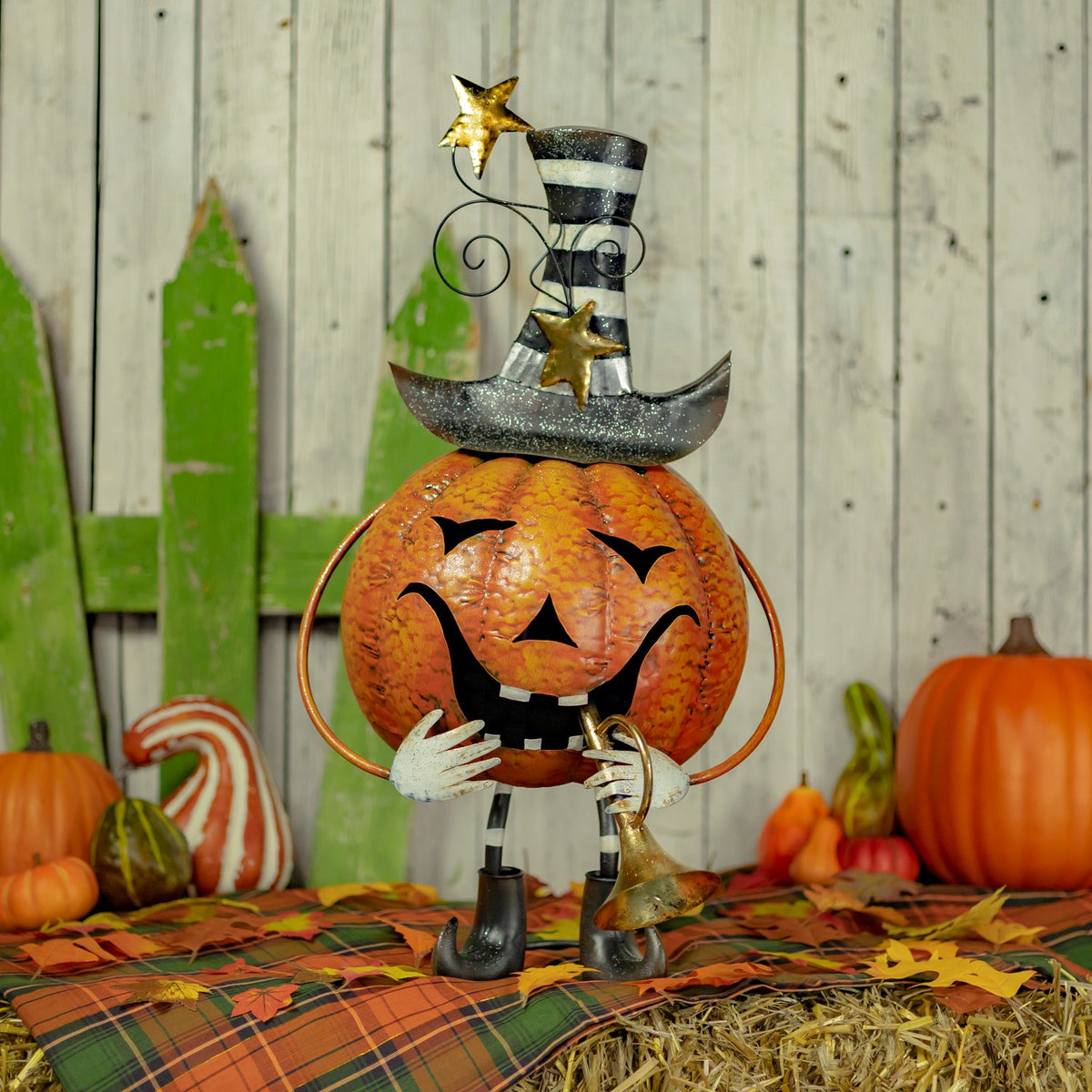 Orange jack-o'-lantern figurine with striped hat and trumpet in a fall display