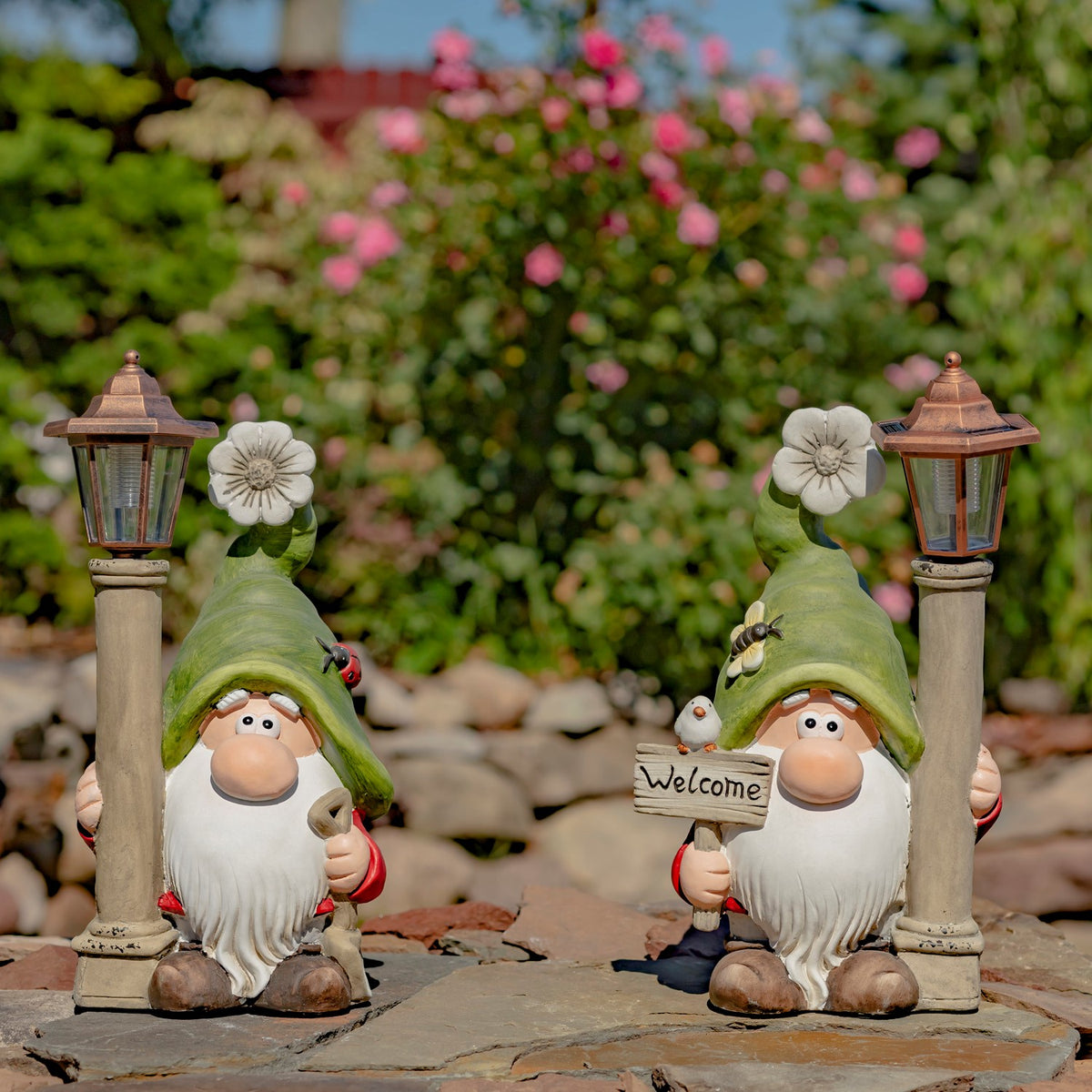 Pair of green-hatted garden gnomes with lanterns displayed on a stone patio