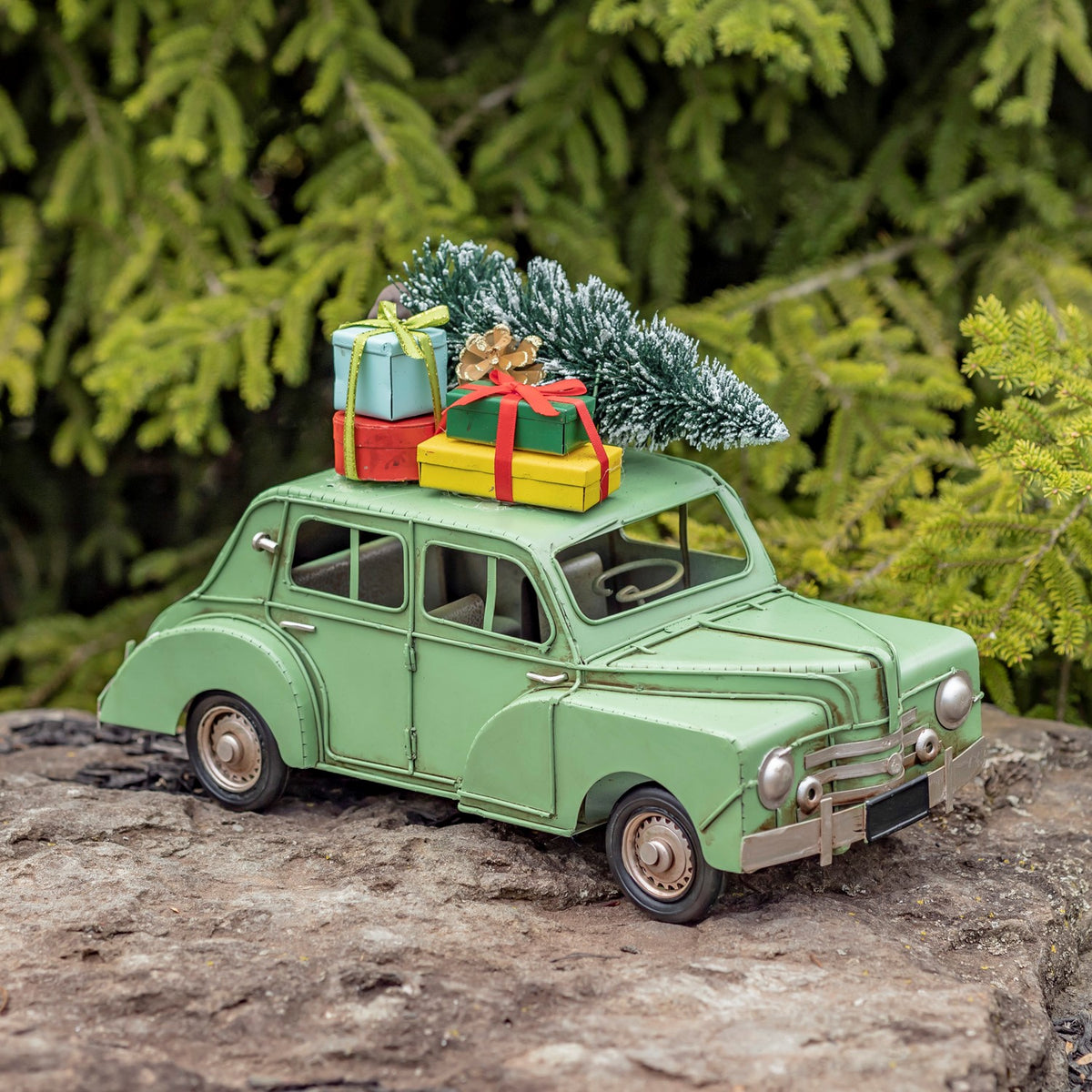 Light green vintage-style car with a tree and gifts on the roof, front angle outdoors