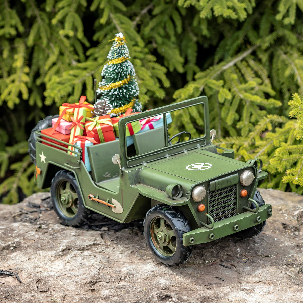 Army-green military vehicle with tree and gifts, angled front view outdoors