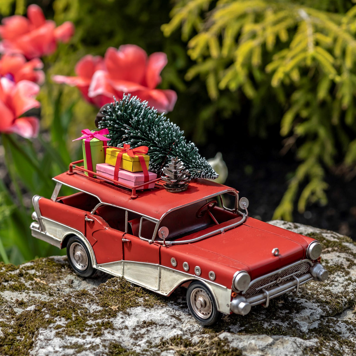 Red-and-ivory vintage-style wagon with tree and gifts, front three-quarter view outdoors