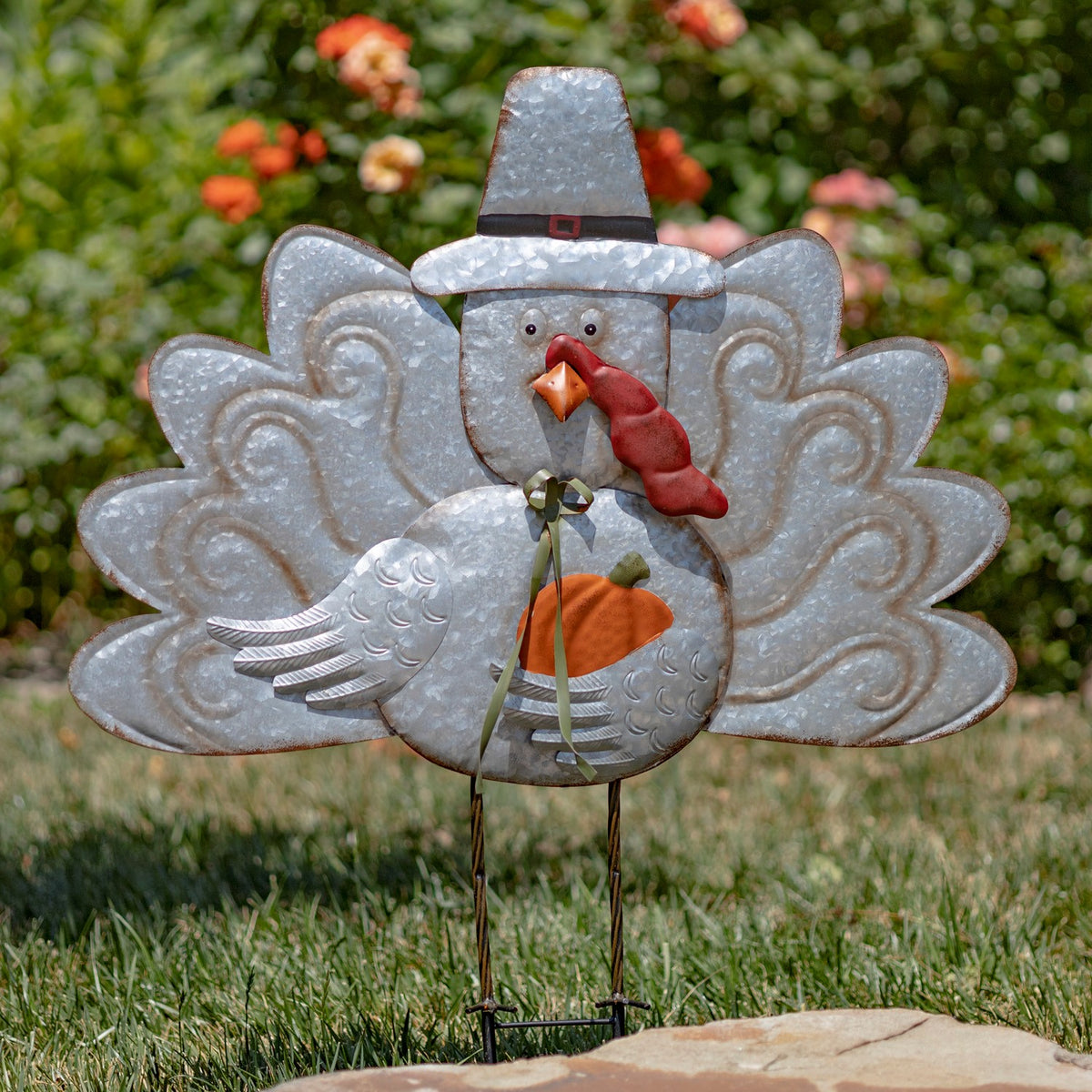 Galvanized turkey garden stake with a pilgrim hat, spread tail feathers and orange breast among flowers.