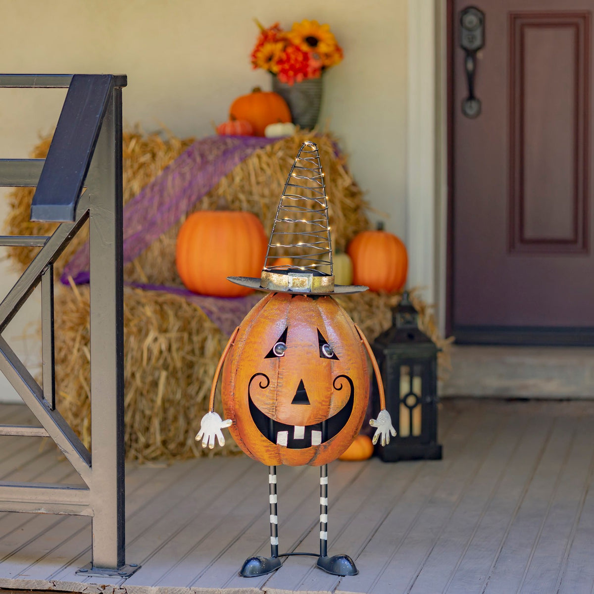 Orange jack-o'-lantern figurine with a spiral witch hat on a decorated porch