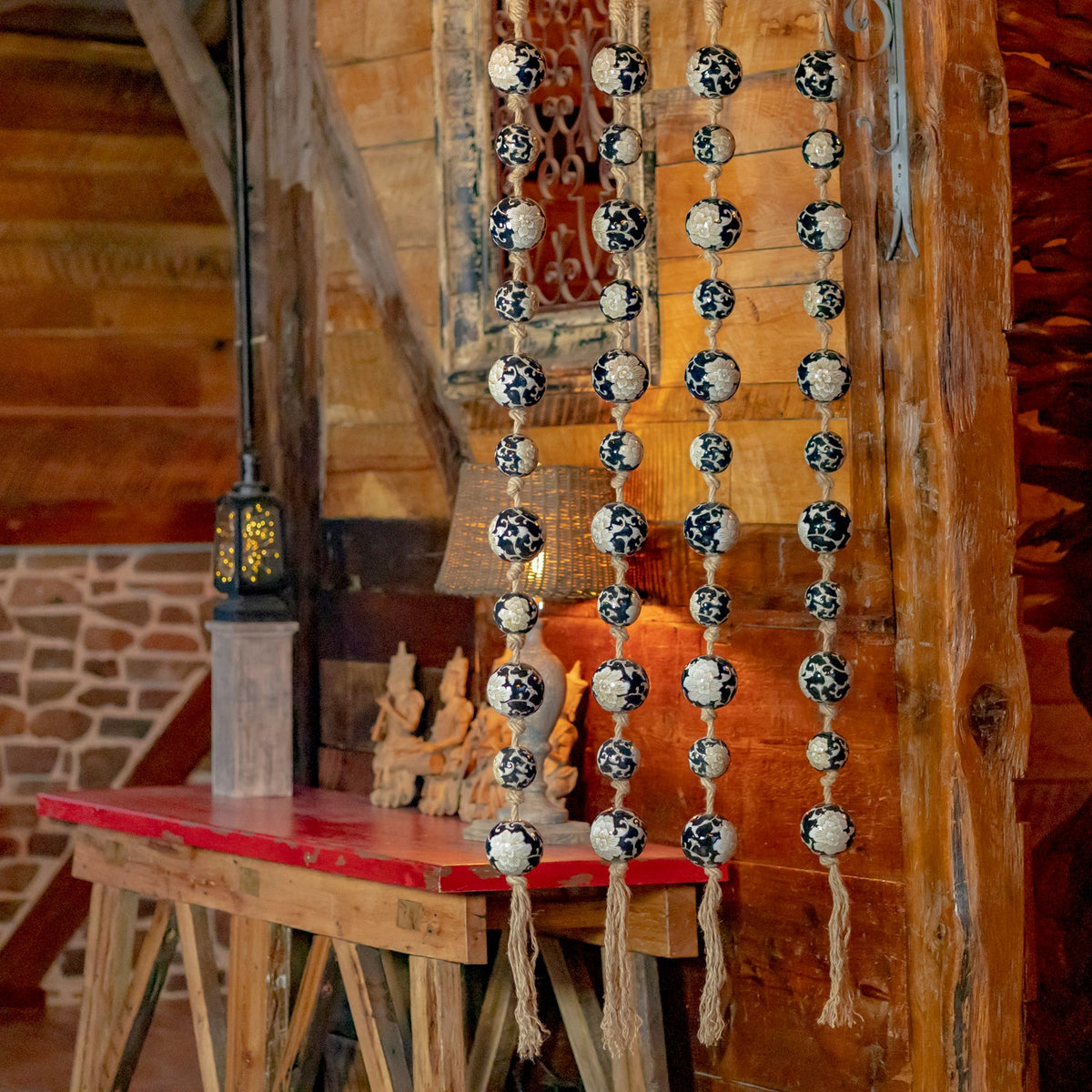 Four strands of black-and-white patterned porcelain balls hang in a rustic wooden room.