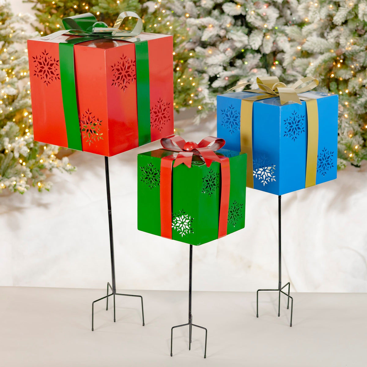 Red, blue, and green gift-box garden stakes shown together in a festive indoor setting