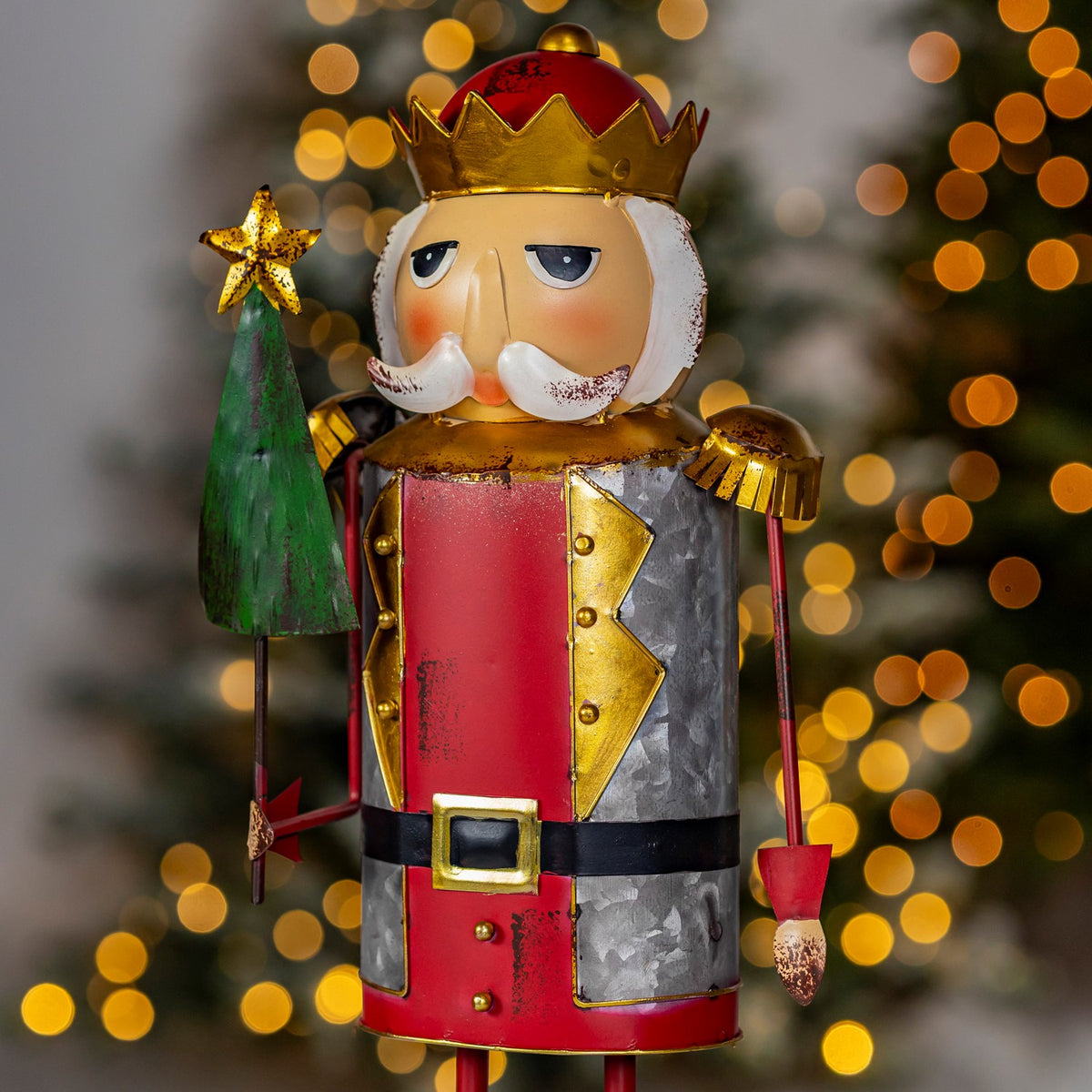 Red and silver nutcracker figurine with a green Christmas tree, shown close up