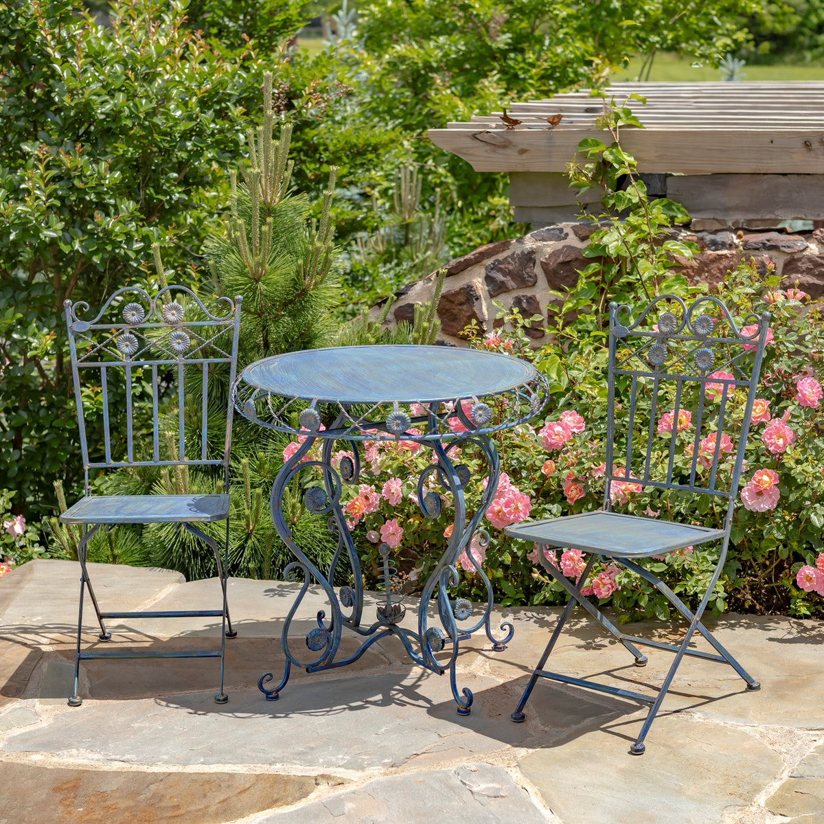 Cobalt blue bistro set arranged on a stone patio beside flowering plants