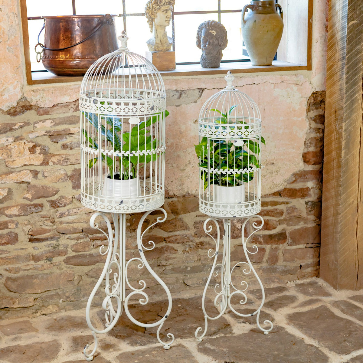 Antique white birdcage decorations with potted plants displayed on stands indoors