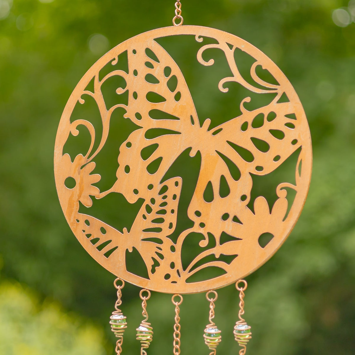 Copper-finish circular wind chime with a large butterfly cutout, shown close up outdoors