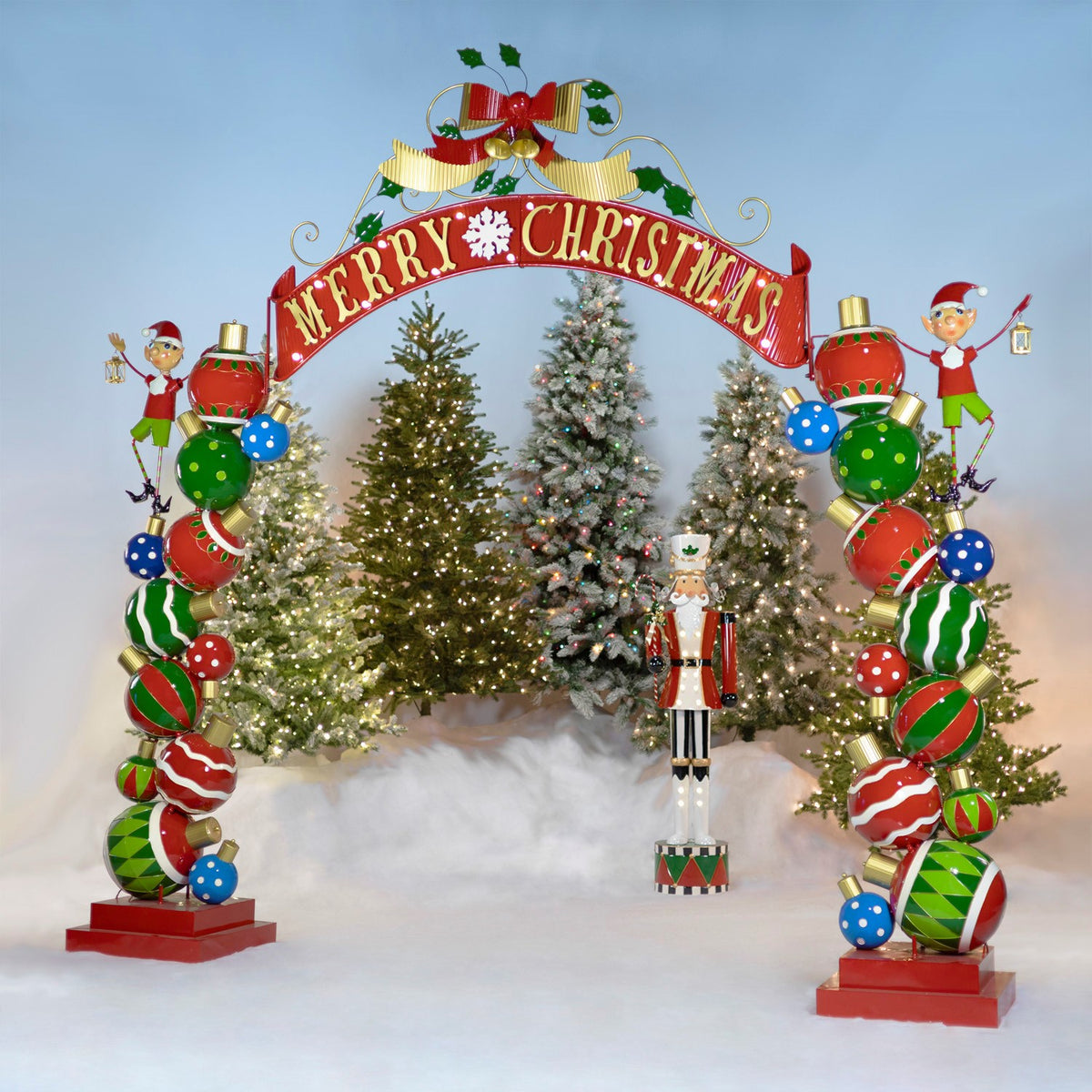 Colorful Christmas archway with elves and lights in front of decorated trees