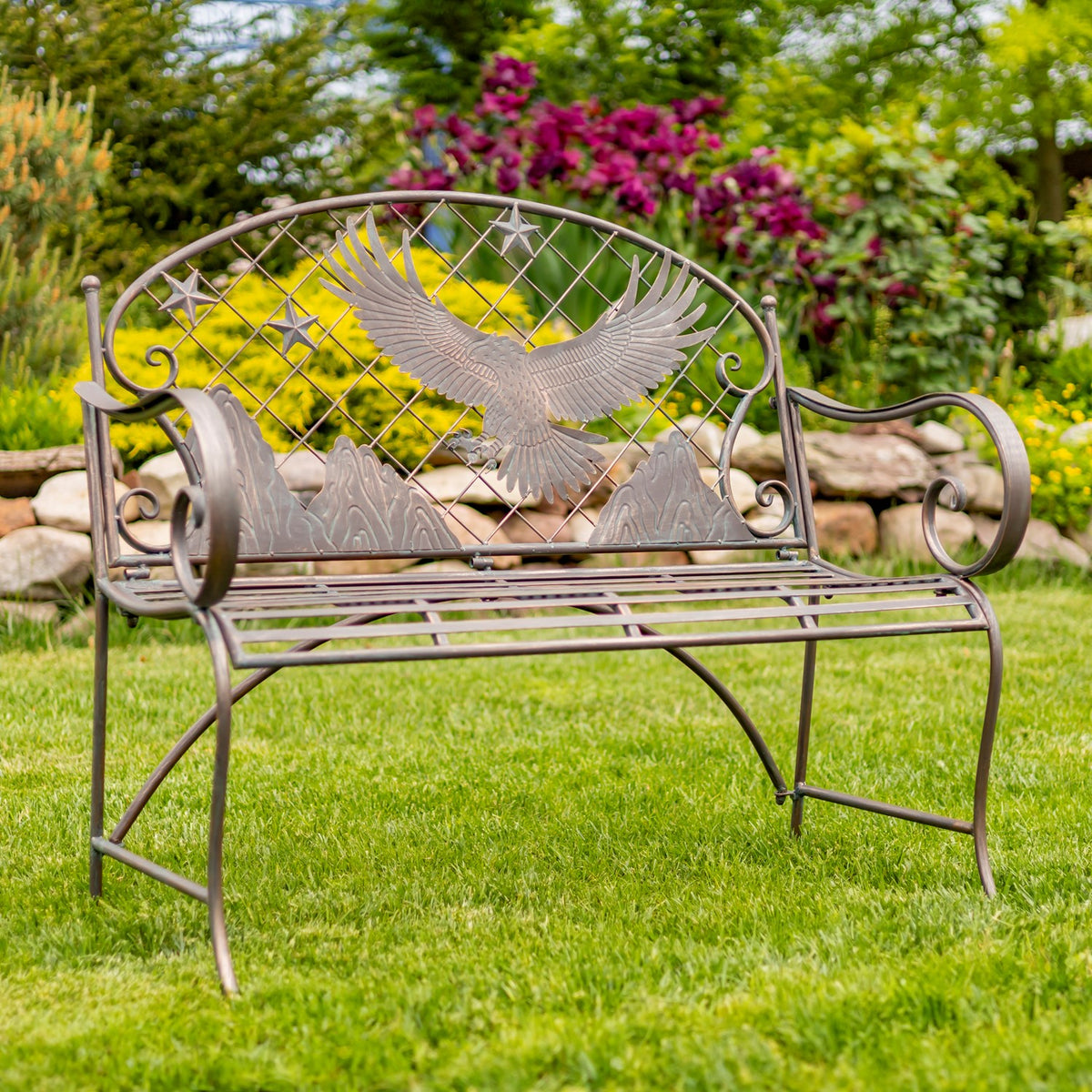 Iron garden bench with a flying eagle backrest, viewed at an angle on a lawn.
