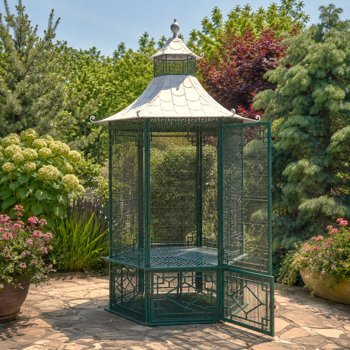 Dark green metal garden gazebo with a pale pagoda-style roof and open doorway on a stone patio.