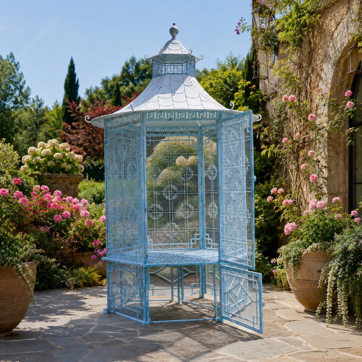 Light blue metal garden gazebo with a pale tiered roof among flowering garden plants.