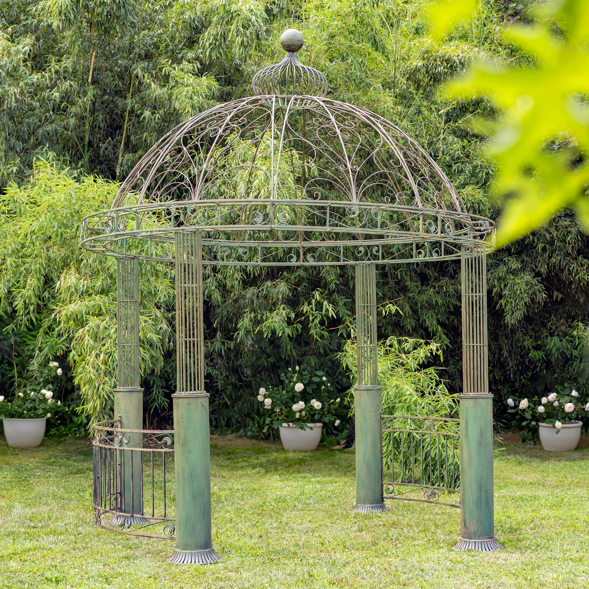 Green-patina iron gazebo with an open domed roof, photographed on a lawn.