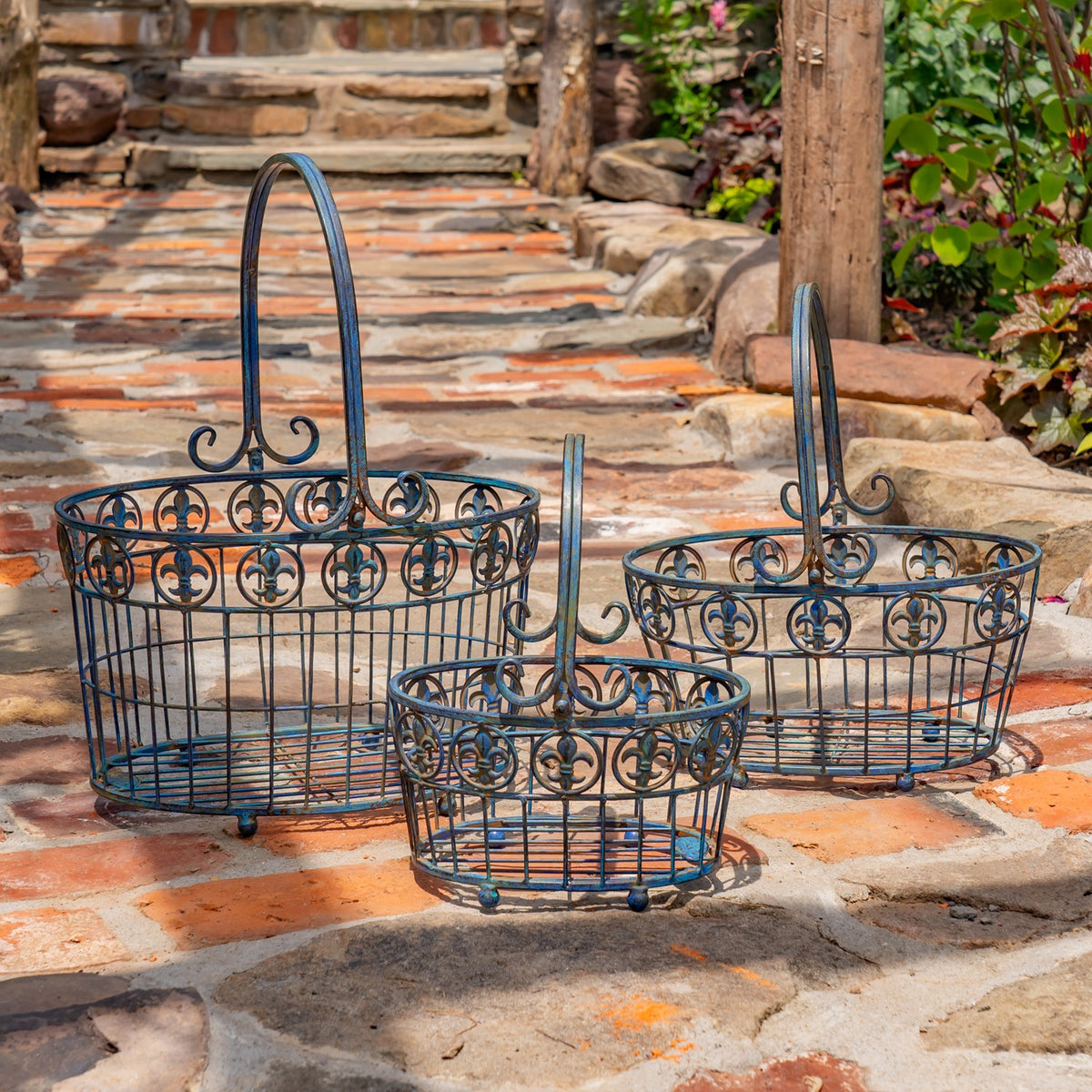 Three dark metal baskets of different sizes displayed on a stone garden path.