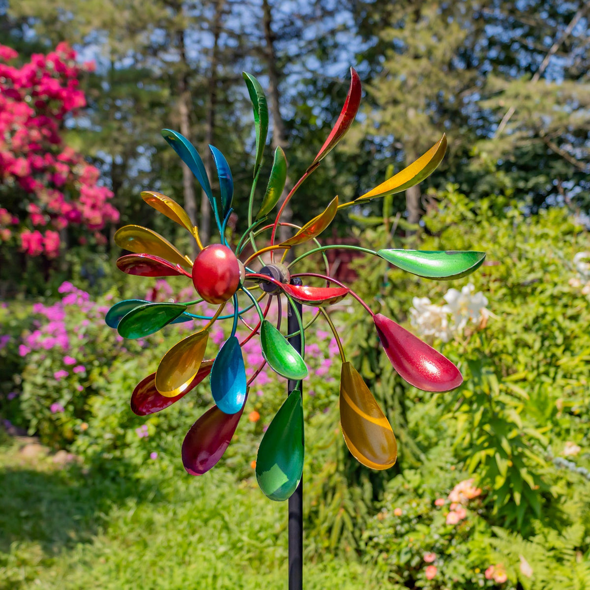 Colorful jewel-tone windmill stake close up in a flowering garden