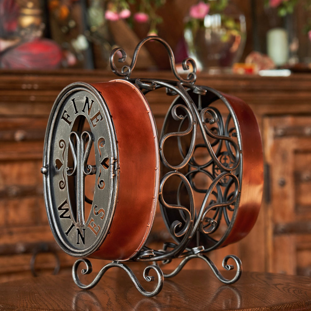 Oval wine rack with ornate black scrollwork and reddish-brown sides on a wooden table.