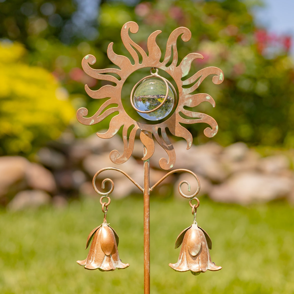 Antique copper garden stake with a swirling sun, glass center, and two hanging lily-shaped bells.