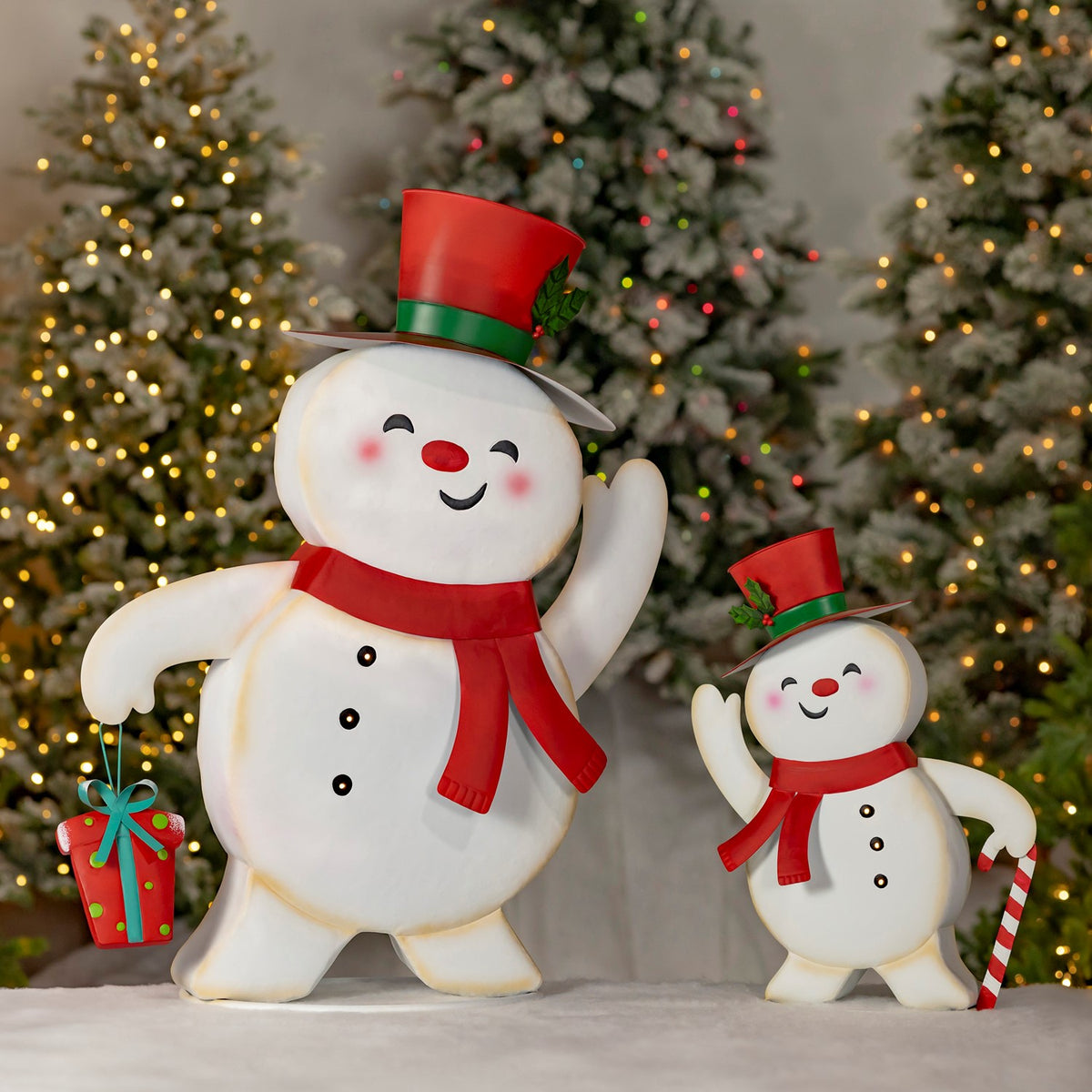 Two smiling snowmen figurines wave beside Christmas trees, one holding a gift and the other a candy cane.
