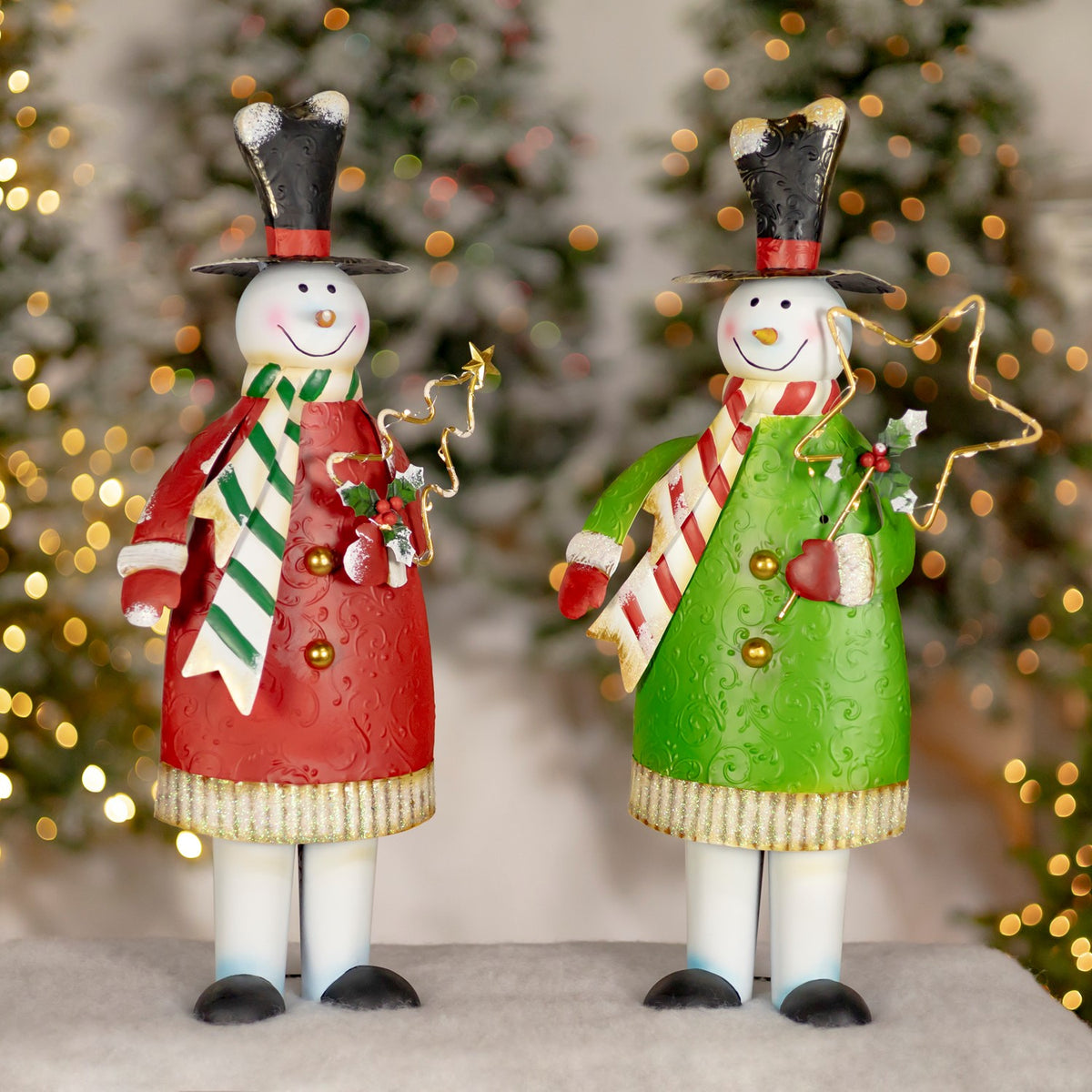 Two snowmen decorations stand side by side in red and green coats, each holding a gold wire star.