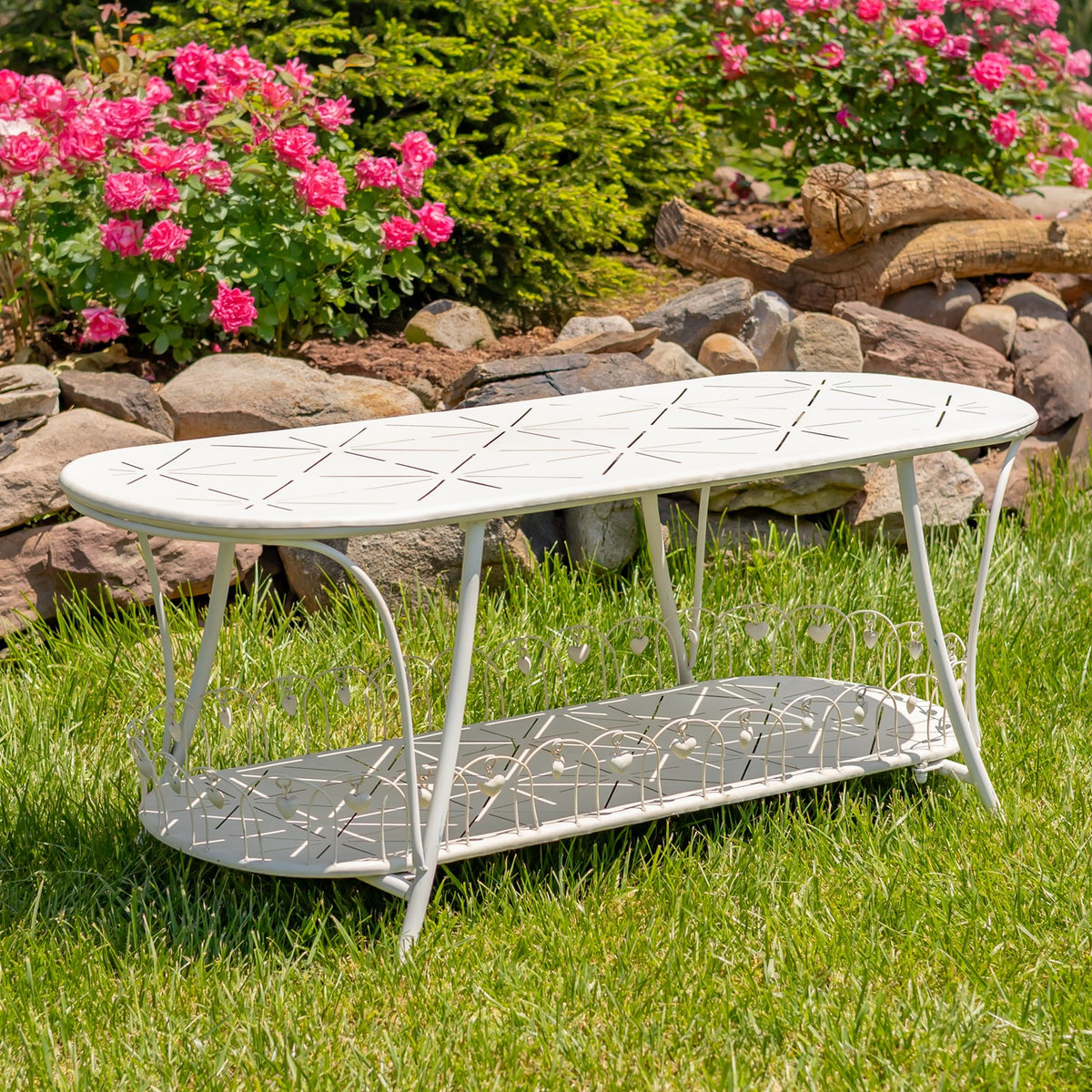 Antique white oval garden table with lower shelf, angled view on grass
