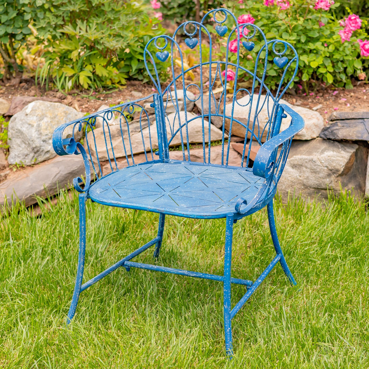 Blue metal garden armchair with decorative heart details on its tall back, photographed on grass.