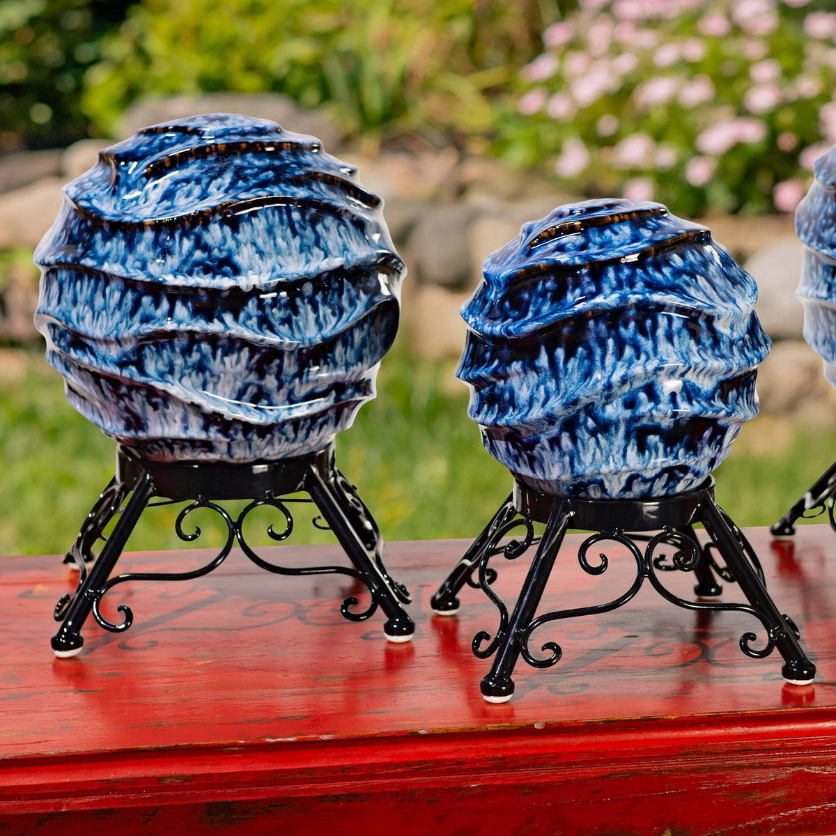 Two blue-and-white ridged globes on black scrollwork stands, with part of a third visible at the edge.