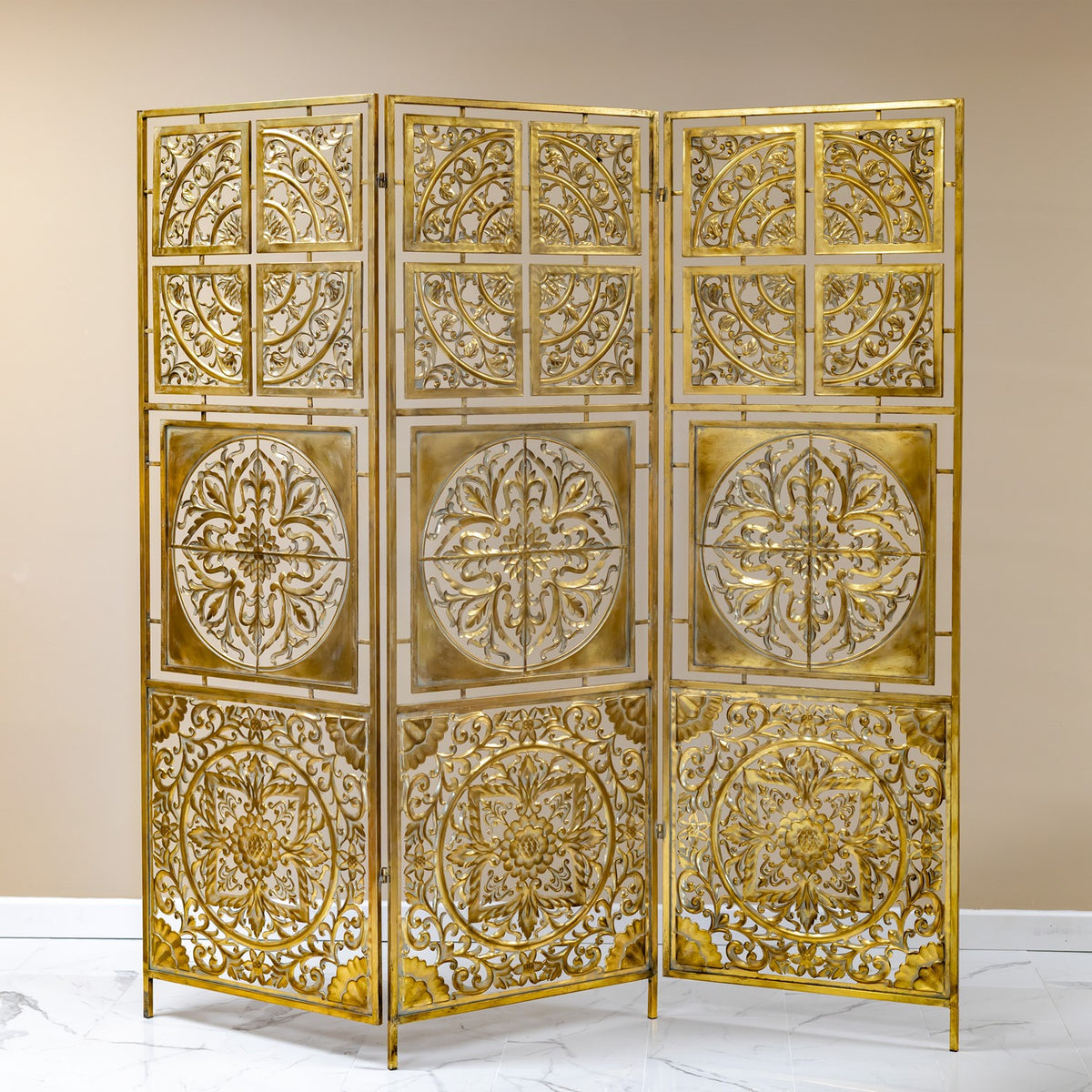 Three-panel gold folding screen with ornate openwork medallions displayed against a light wall.