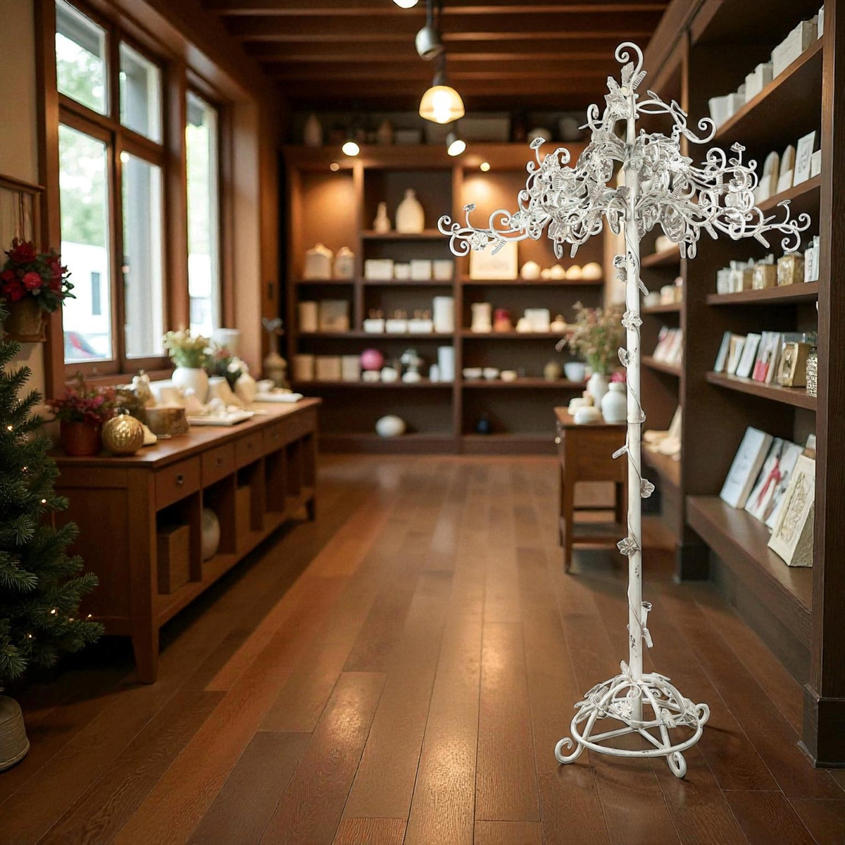 An ornate white iron display tree stands on a circular base in a warmly lit wood-paneled shop.