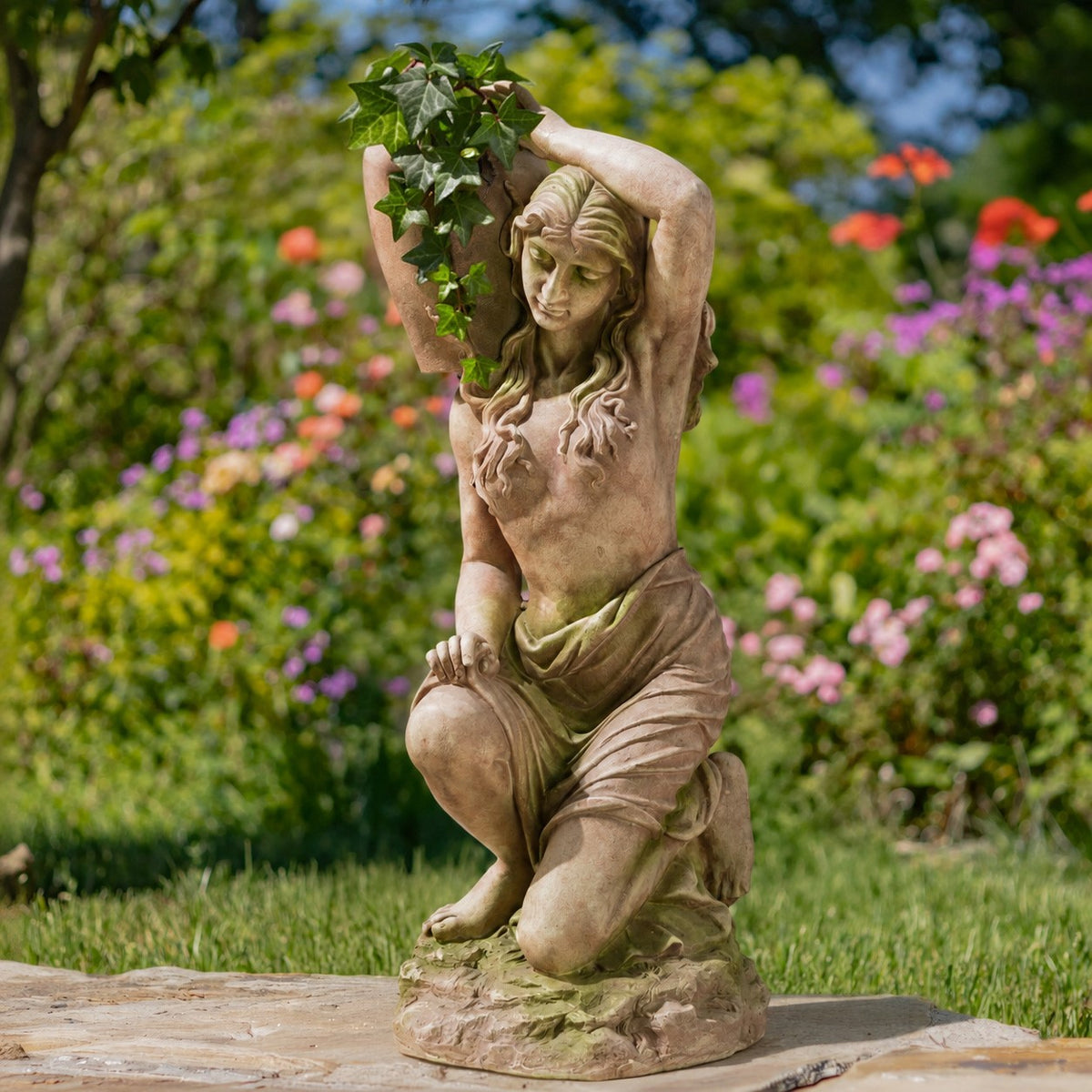Front view of the kneeling statue with leafy greenery rising from the urn above her head.