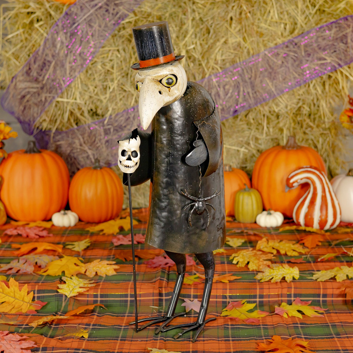 Black-and-white vulture figurine in a top hat among pumpkins and autumn decor