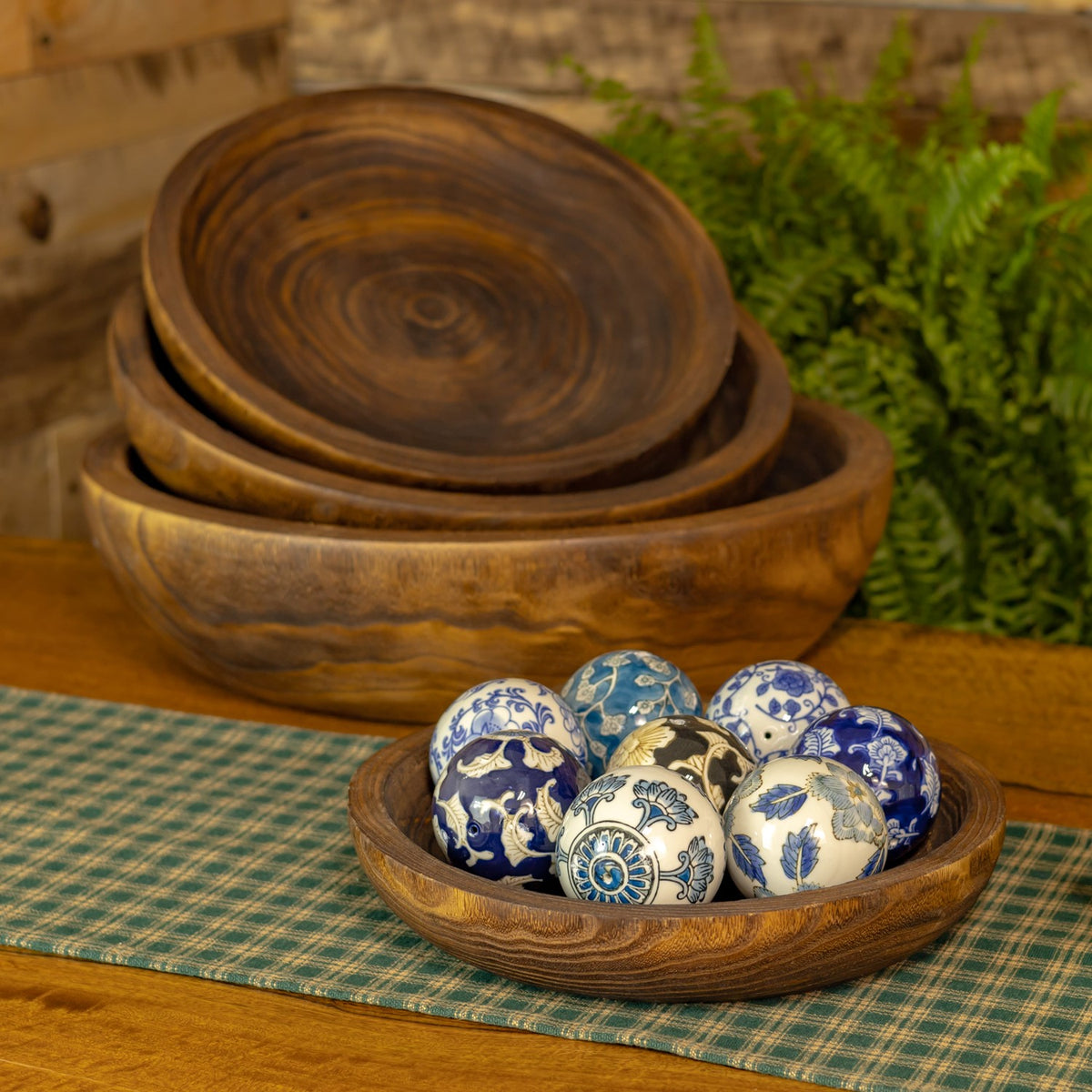 Four round wooden trays nested together, with patterned decorative balls arranged in the smallest tray.