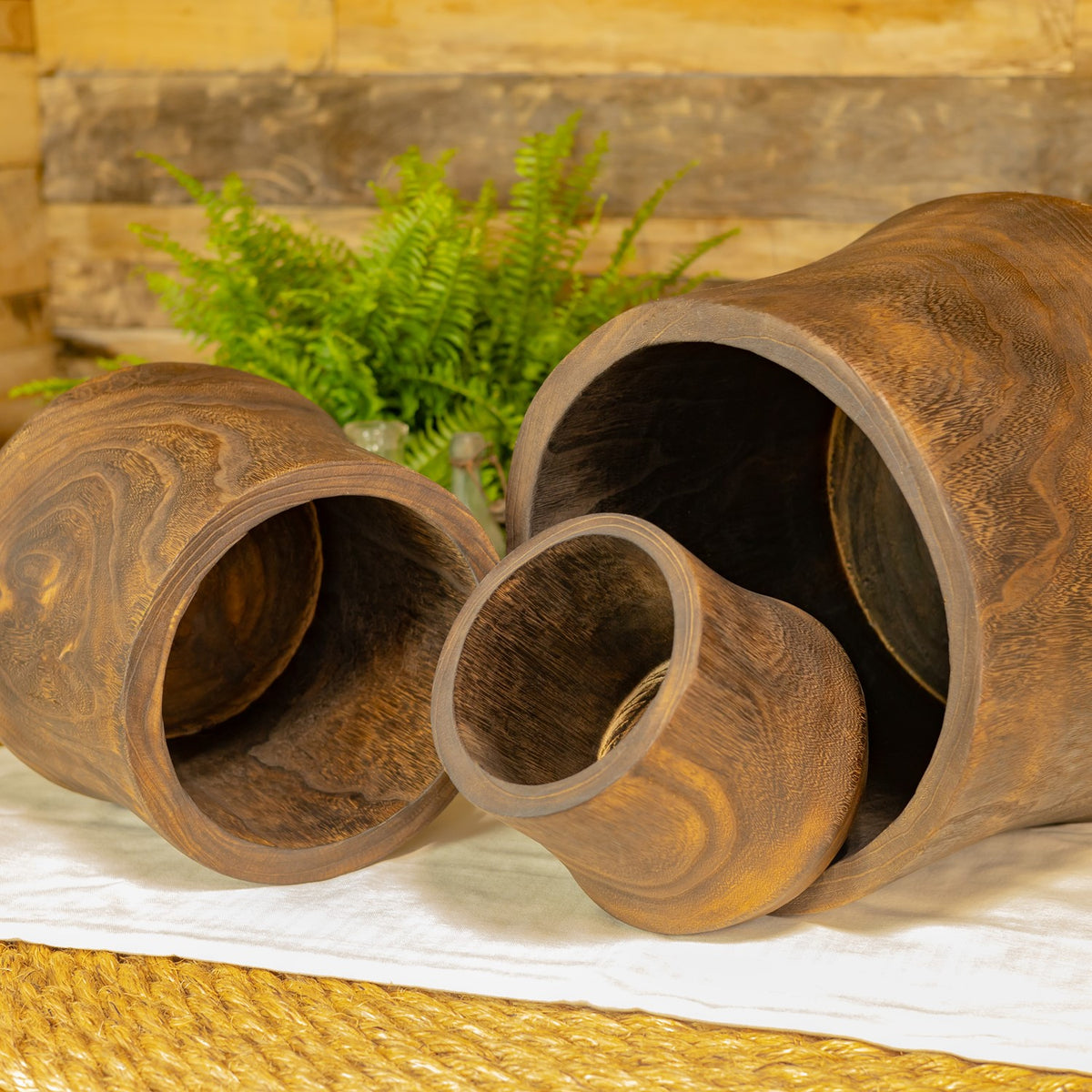 Three round wooden bowls lie on their sides, showing their open interiors and swirling grain.