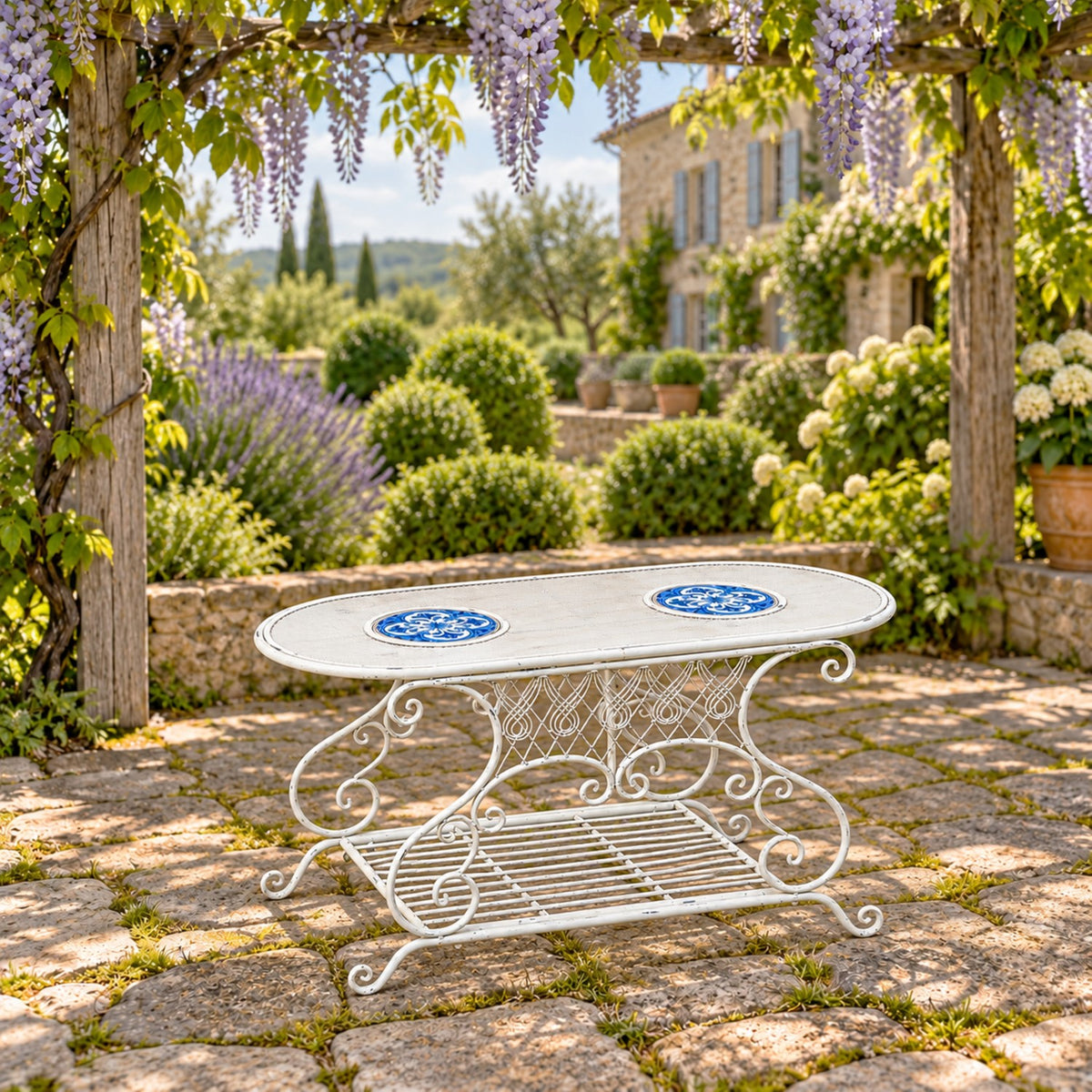 White oval metal garden table with blue mosaic insets and a lower slatted shelf on a stone patio.