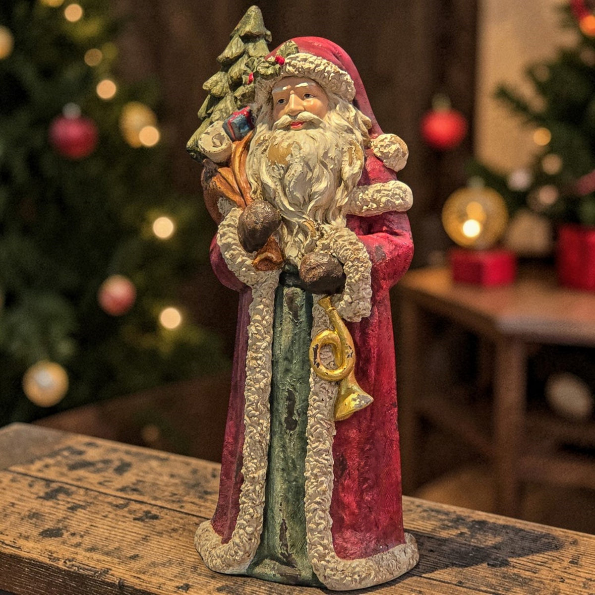 Full Santa figurine with a decorated tree and horn on a wooden table