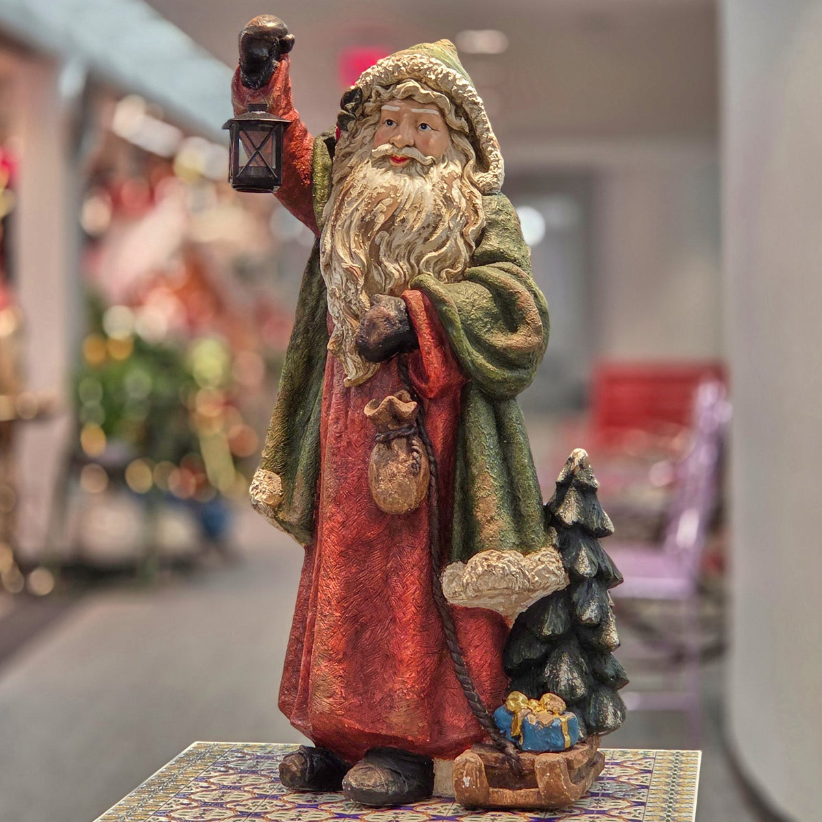 Full view of multicolor Santa figurine holding a lantern beside a tree